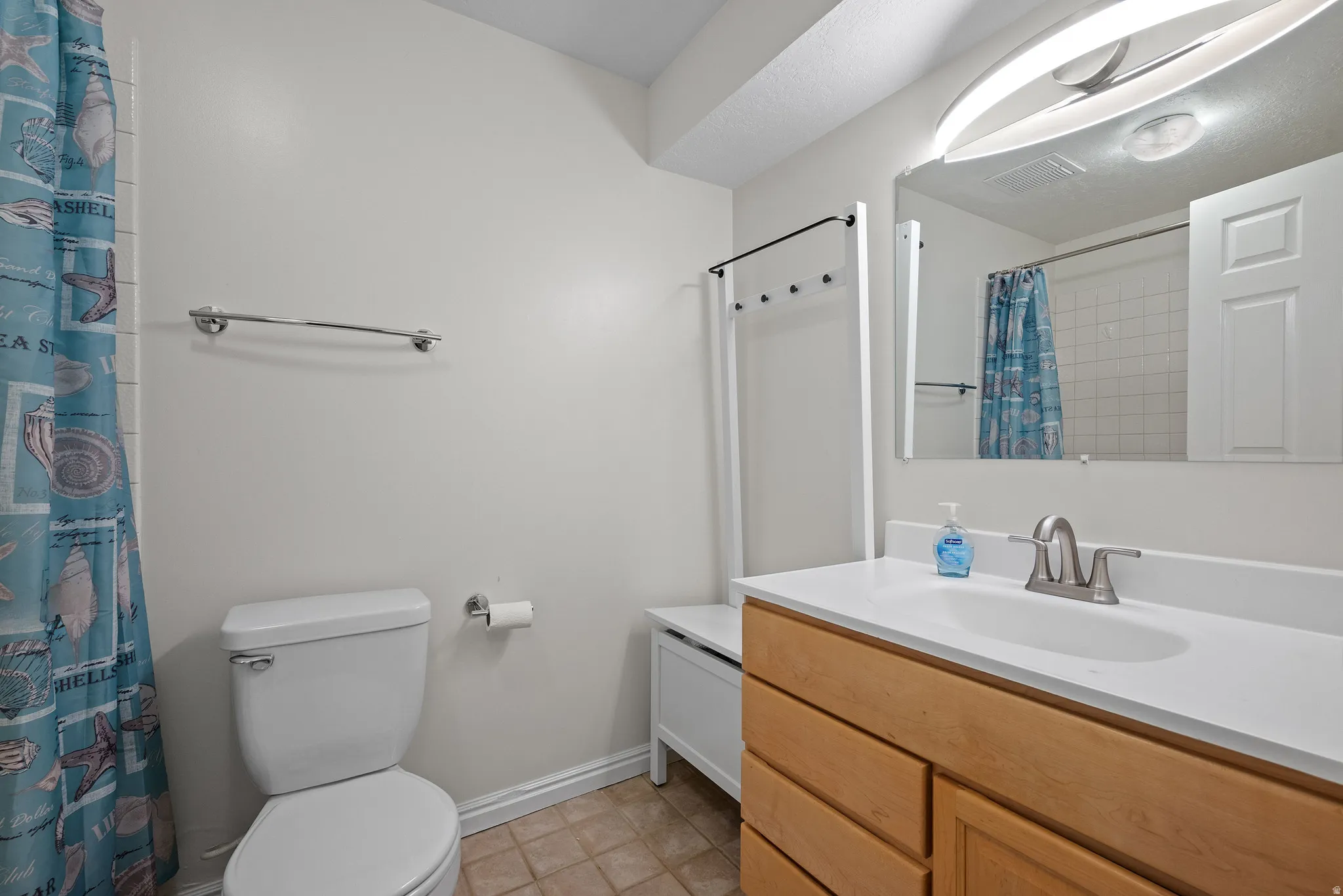 Bathroom featuring a vanity with wood-finish cabinetry, a white countertop, and an undermount sink