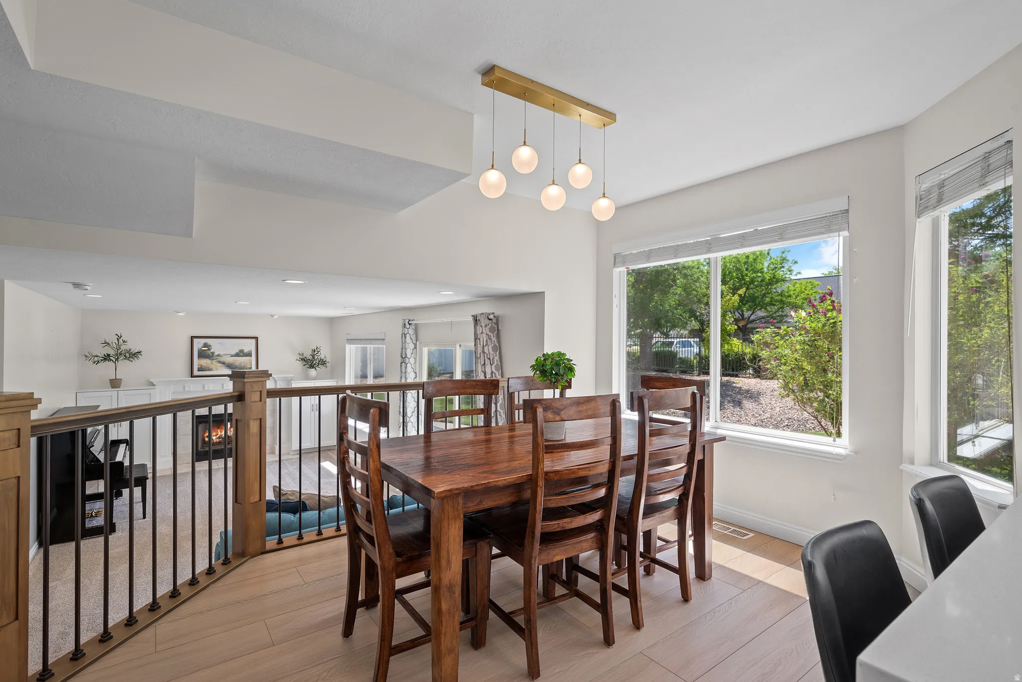 Dining area featuring large windows, wood-finish flooring, and a contemporary linear chandelier with globe pendants
