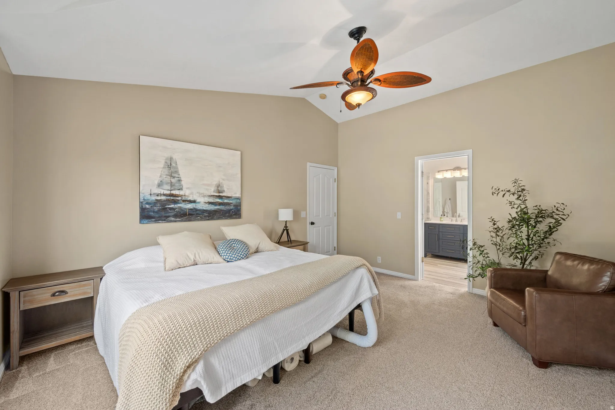 Carpeted bedroom featuring vaulted ceilings and a ceiling fan with integrated lighting
