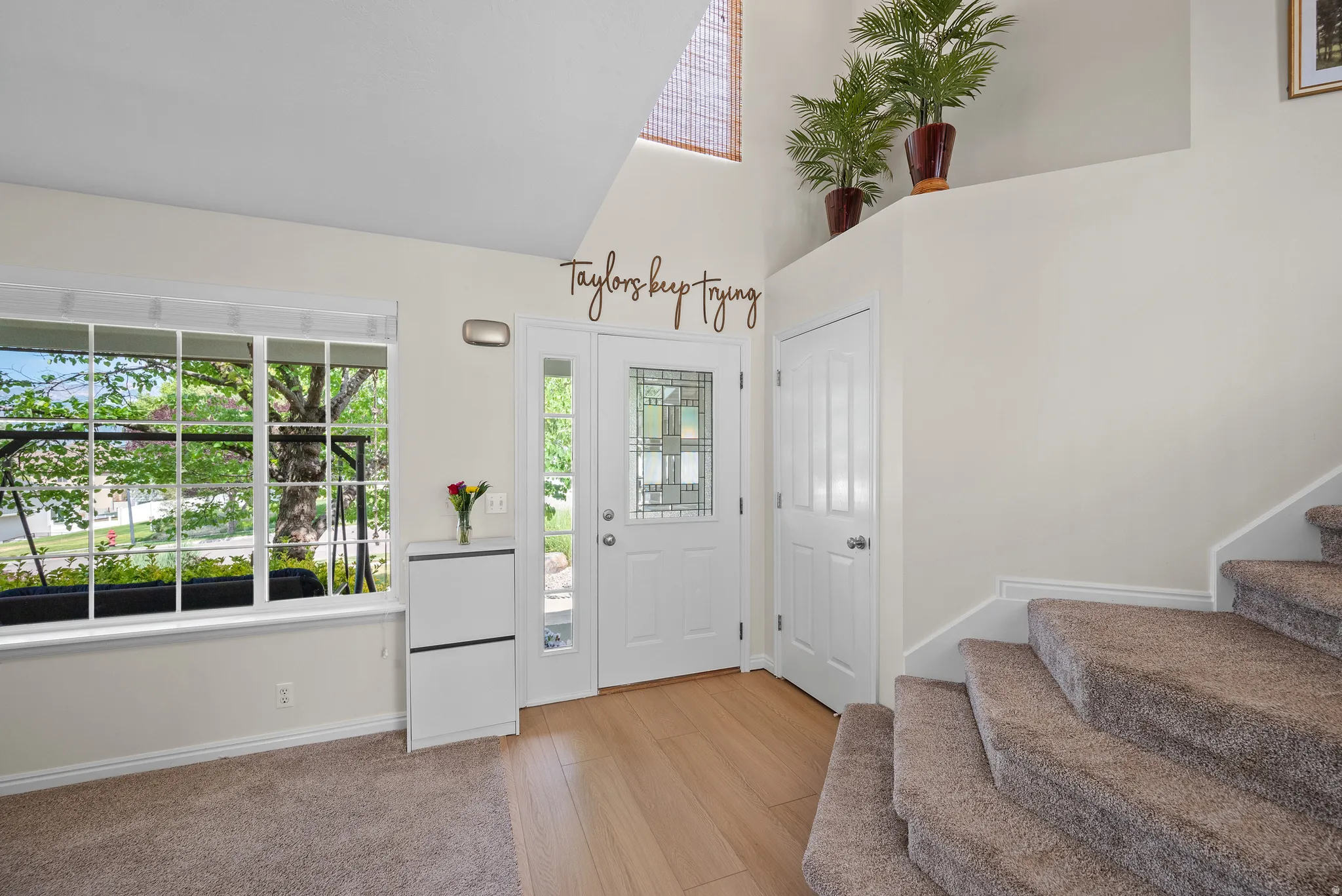 Entryway featuring wood-finish flooring, a white front door with decorative glass inserts, and a prominent picture window