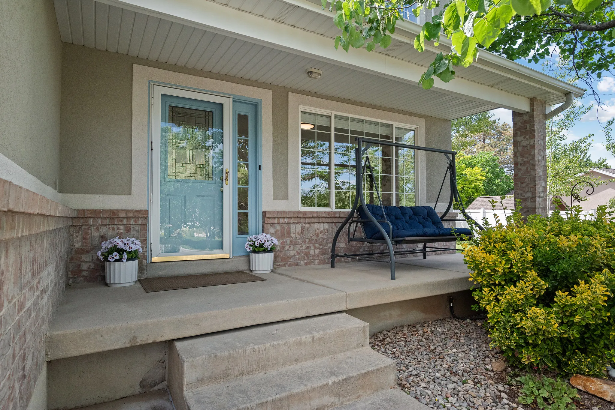 Inviting covered front porch featuring a light blue entry door, sidelight window, and decorative transom