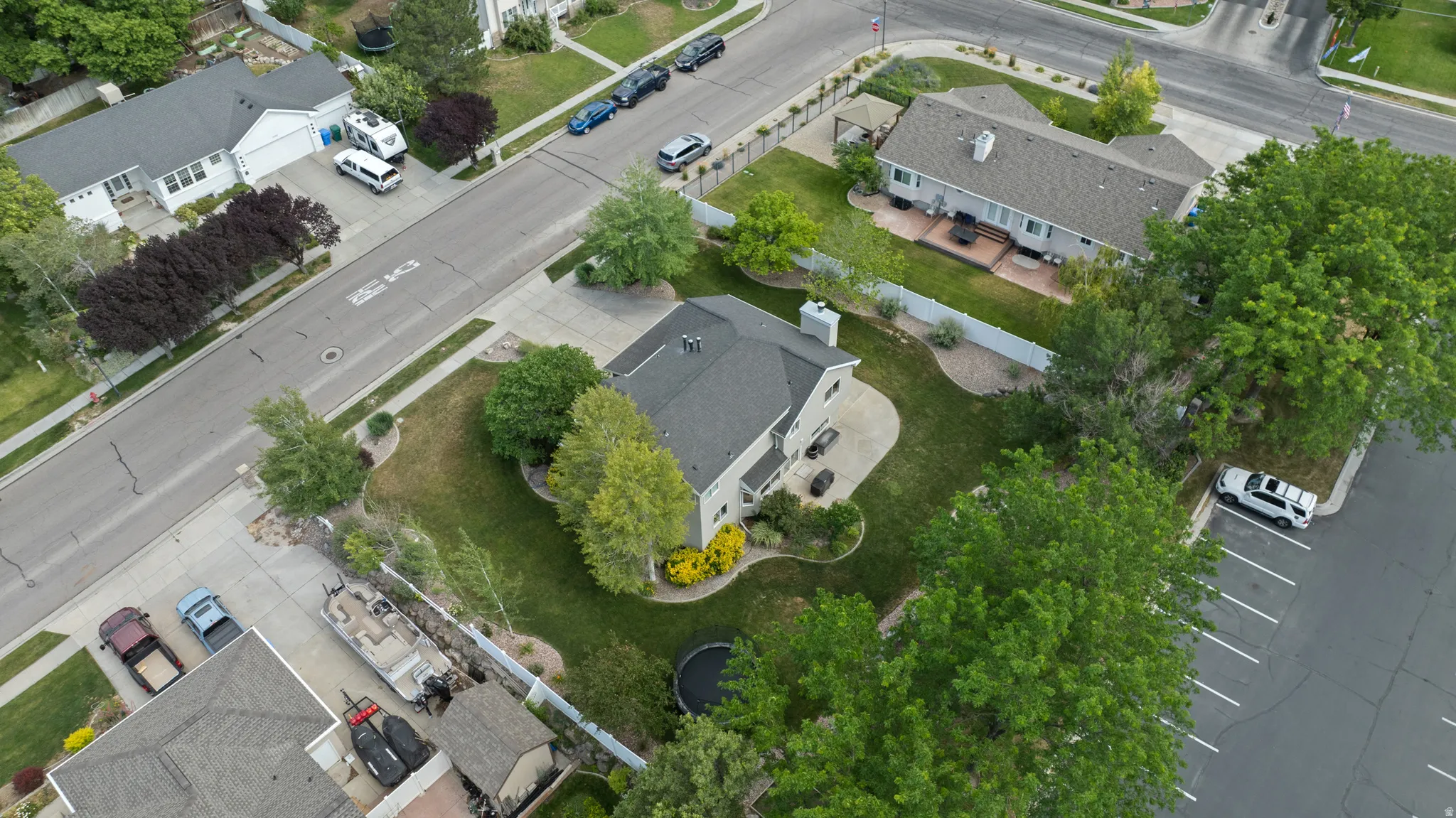 Expansive lot featuring a single-story residence with a gray shingled roof, a manicured lawn, and mature trees