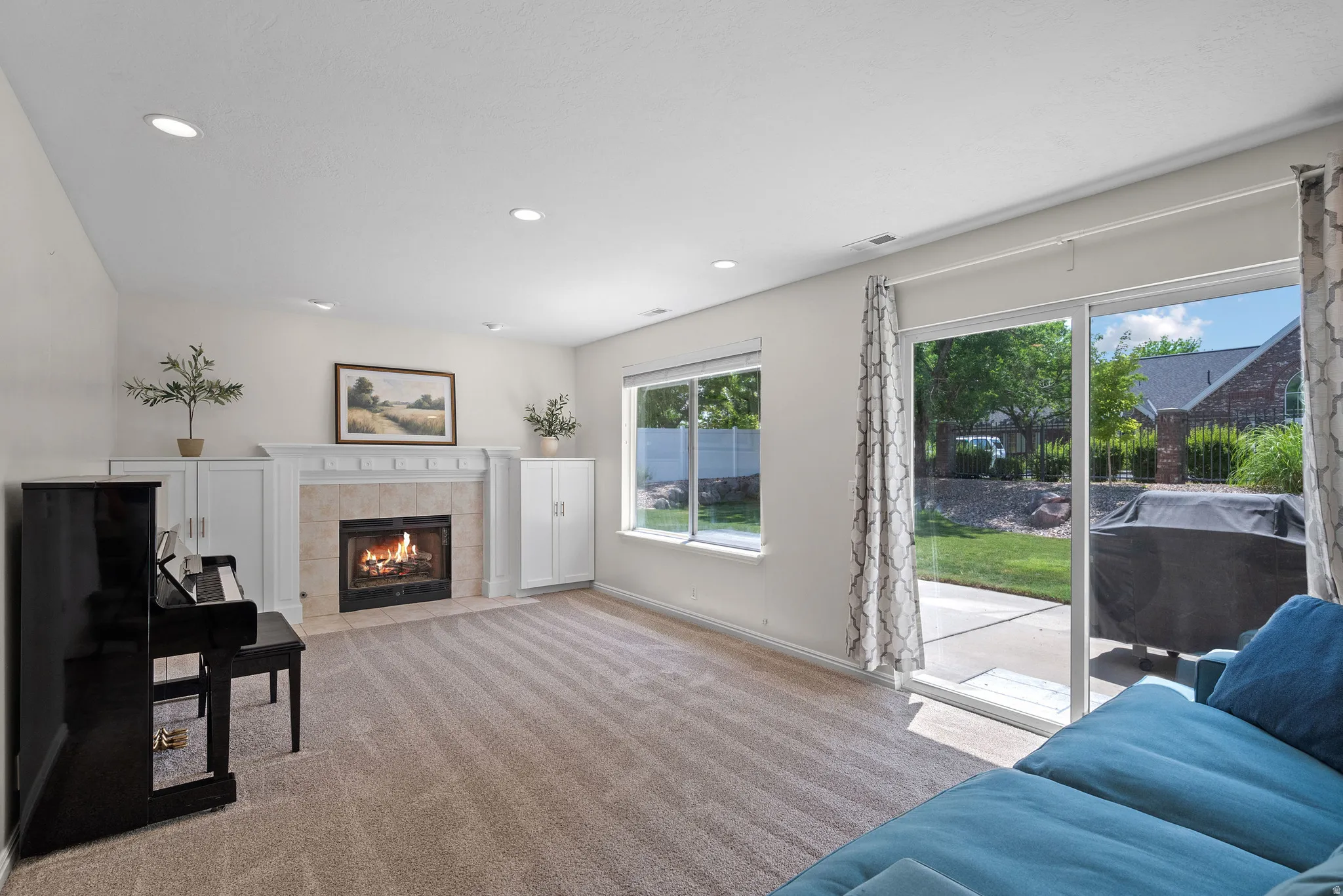 Living area featuring a gas fireplace with a tiled surround and mantle, flanked by built-in white cabinetry