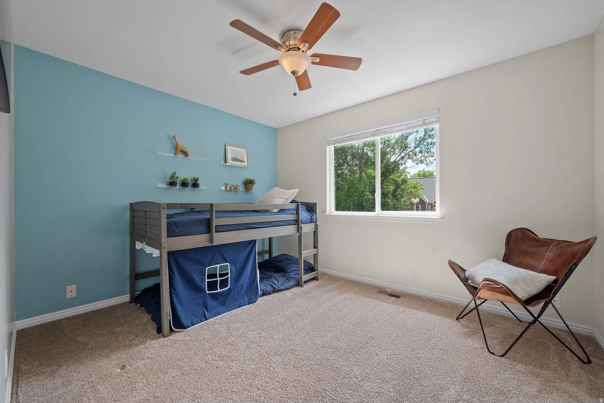 Carpeted room with a ceiling fan, a window, and a light blue accent wall