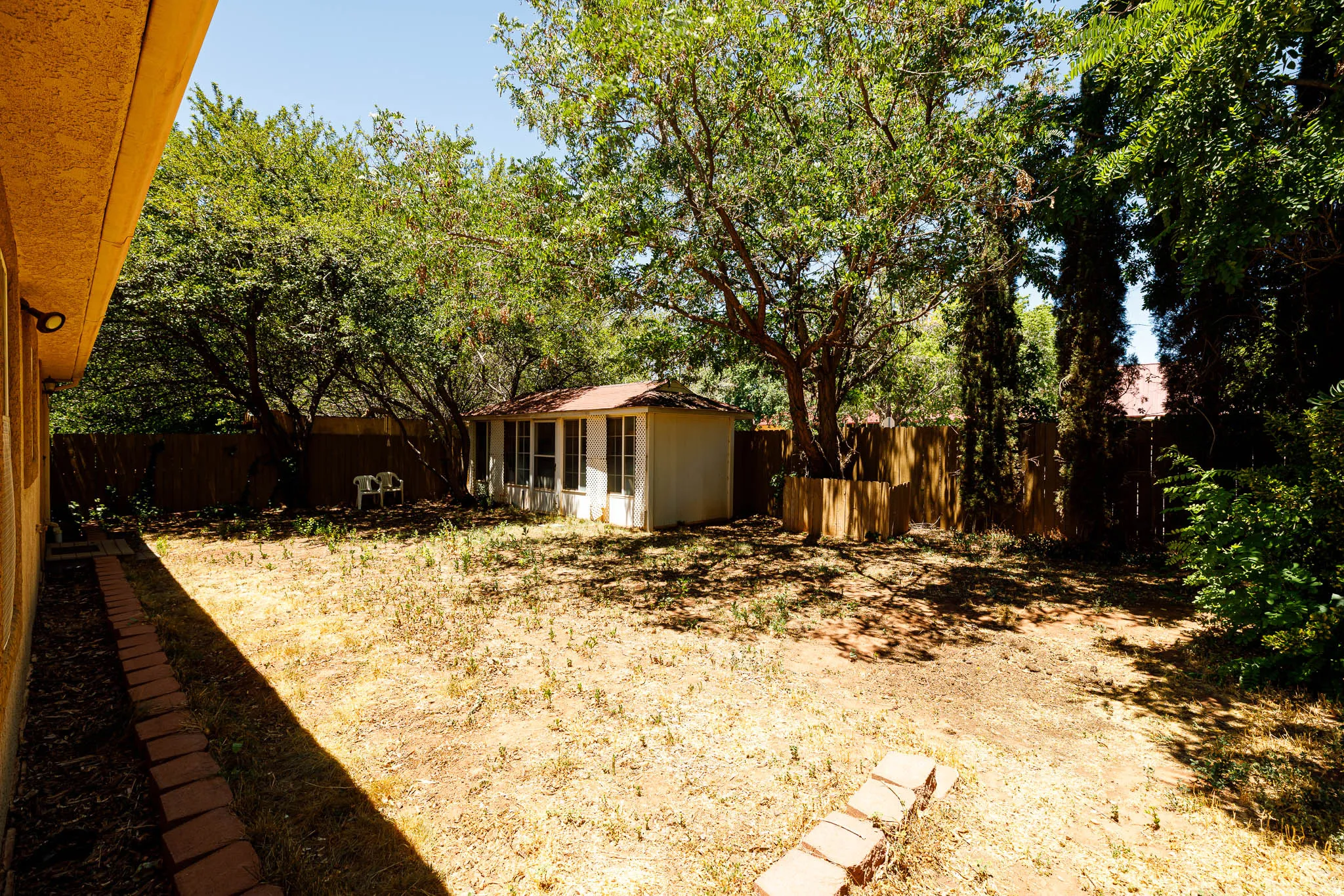 Expansive backyard with mature trees, a privacy fence, and a detached shed