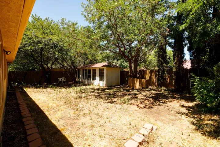 Expansive backyard with mature trees, a privacy fence, and a detached shed