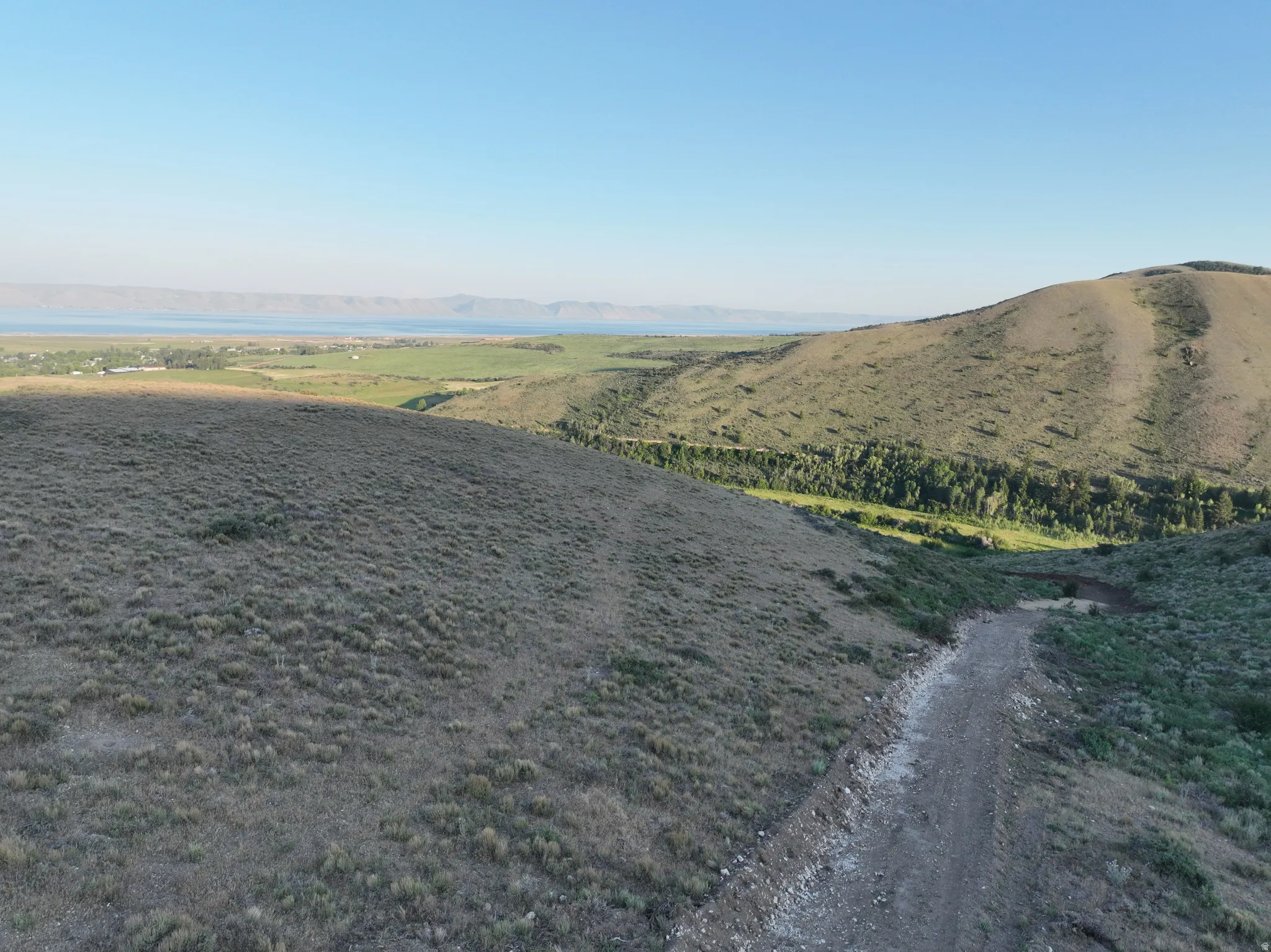 Expansive land featuring a natural terrain, distant lake, and rolling hills