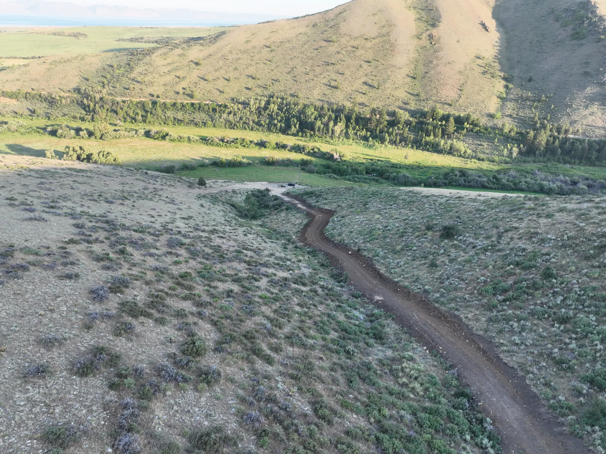 Winding dirt road traversing rolling, brush-covered terrain