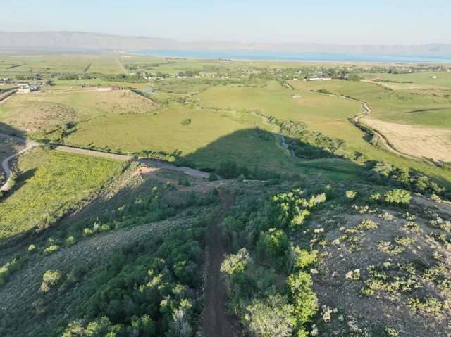 Expansive rural landscape featuring rolling hills, green fields, and distant water