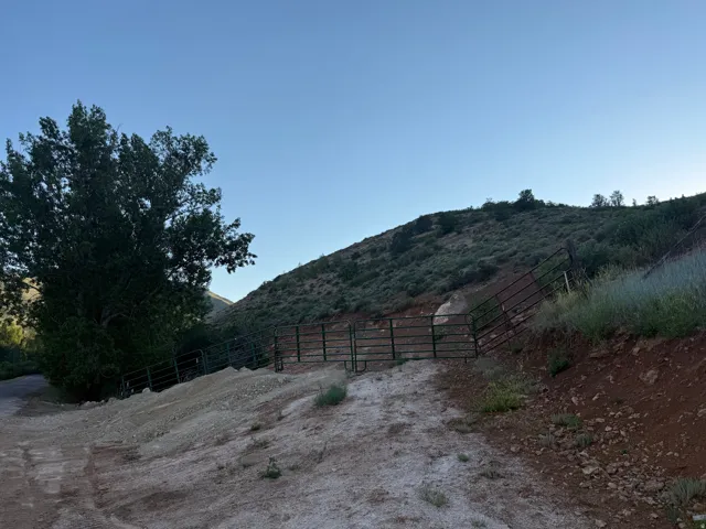 Gated property entrance with a sloped, natural terrain