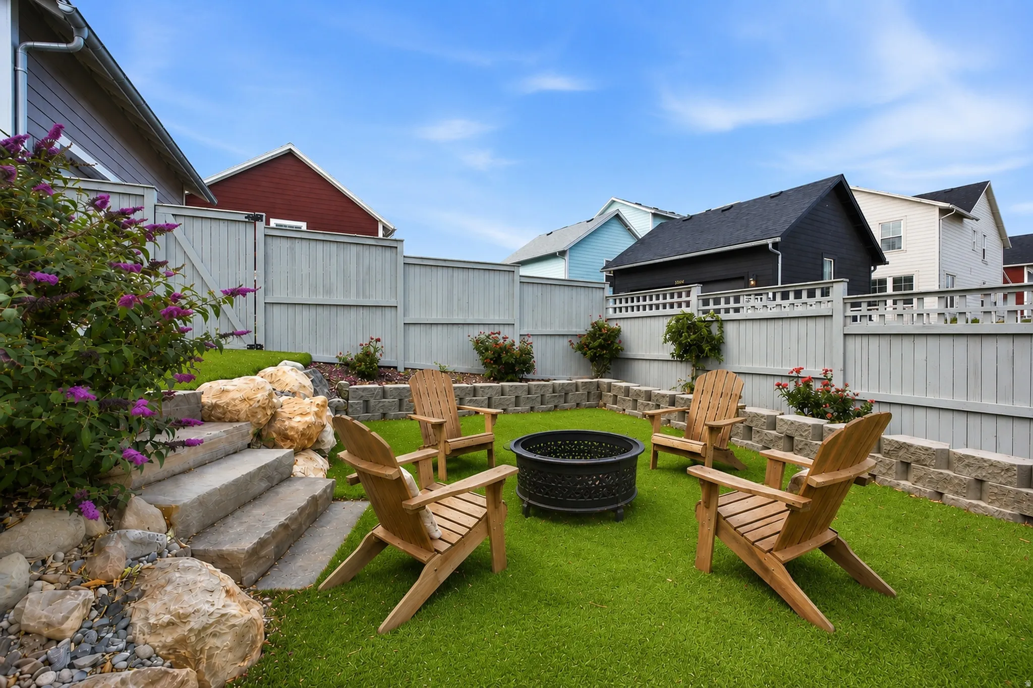 Landscaped yard featuring a circular artificial turf area with a central fire pit