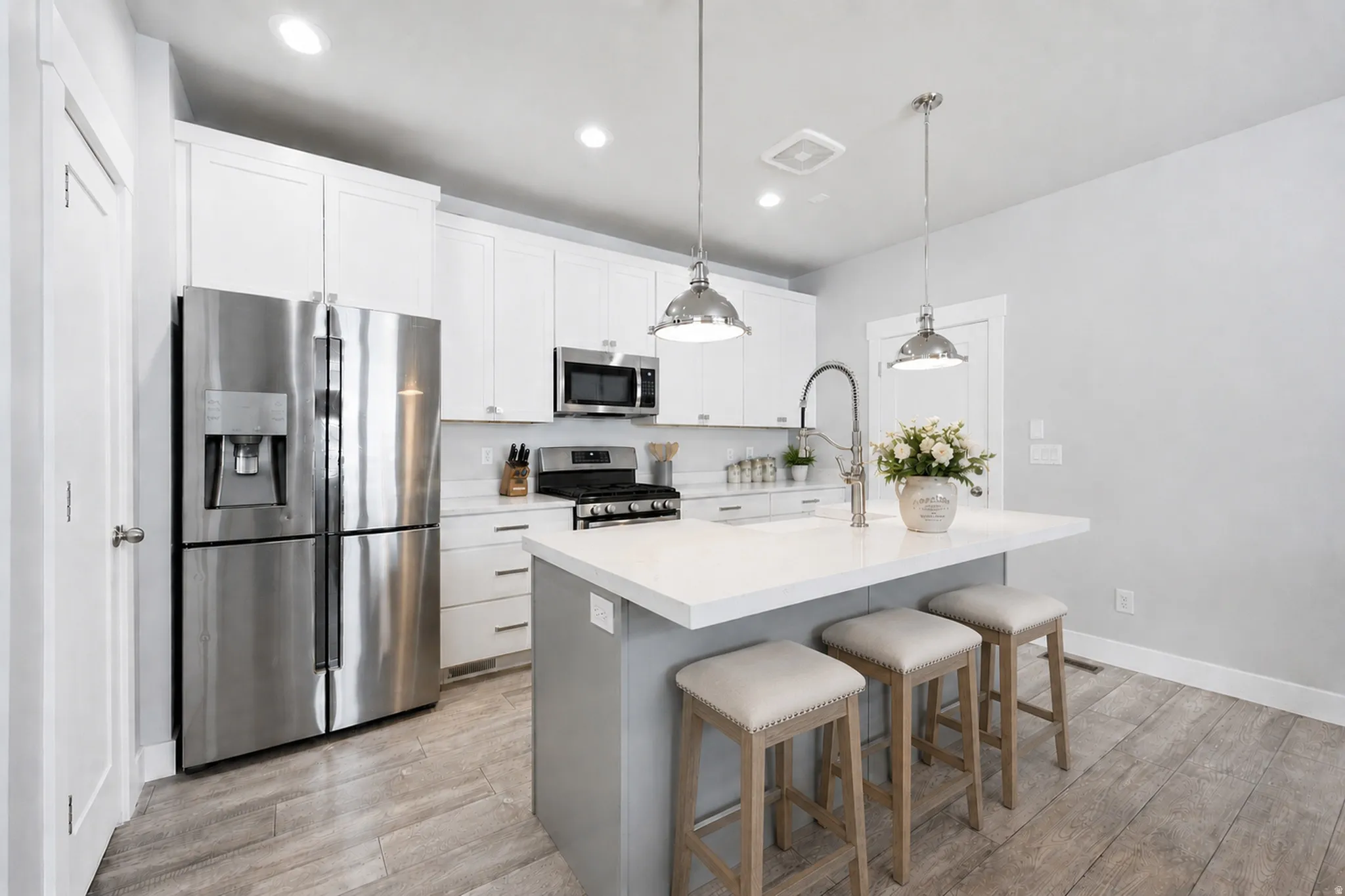 Modern kitchen featuring white shaker cabinetry, stainless steel appliances, and a central island with a white countertop