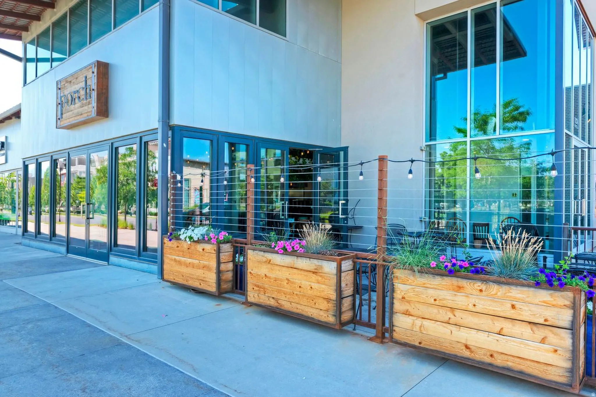 Contemporary storefront with floor-to-ceiling windows, prominent signage, and an outdoor patio area