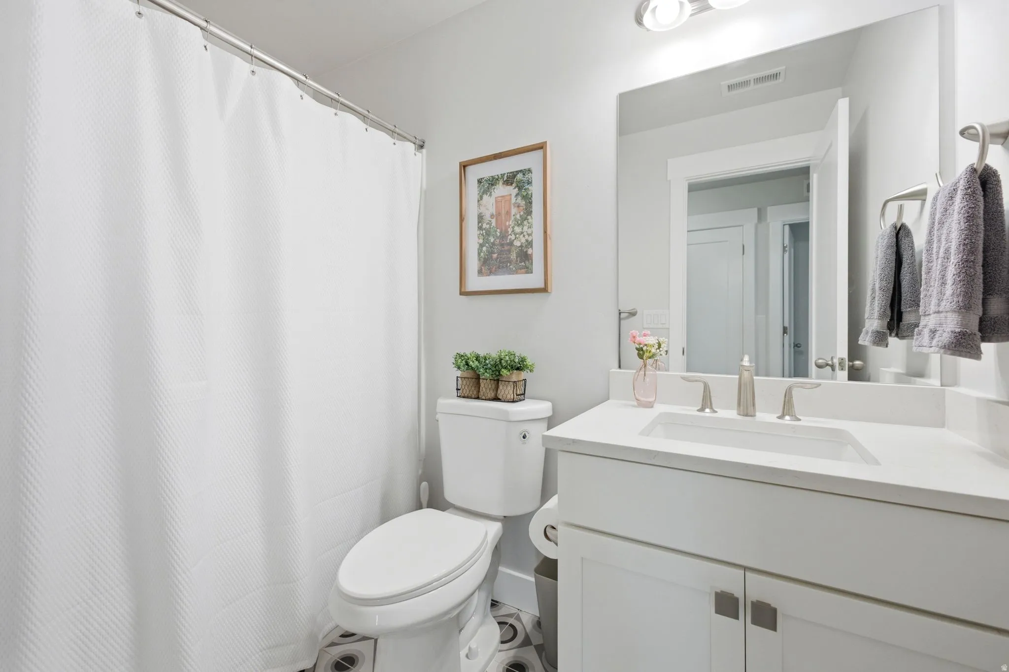 Bathroom featuring a white vanity with an integrated sink, brushed nickel fixtures, and a coordinating mirror