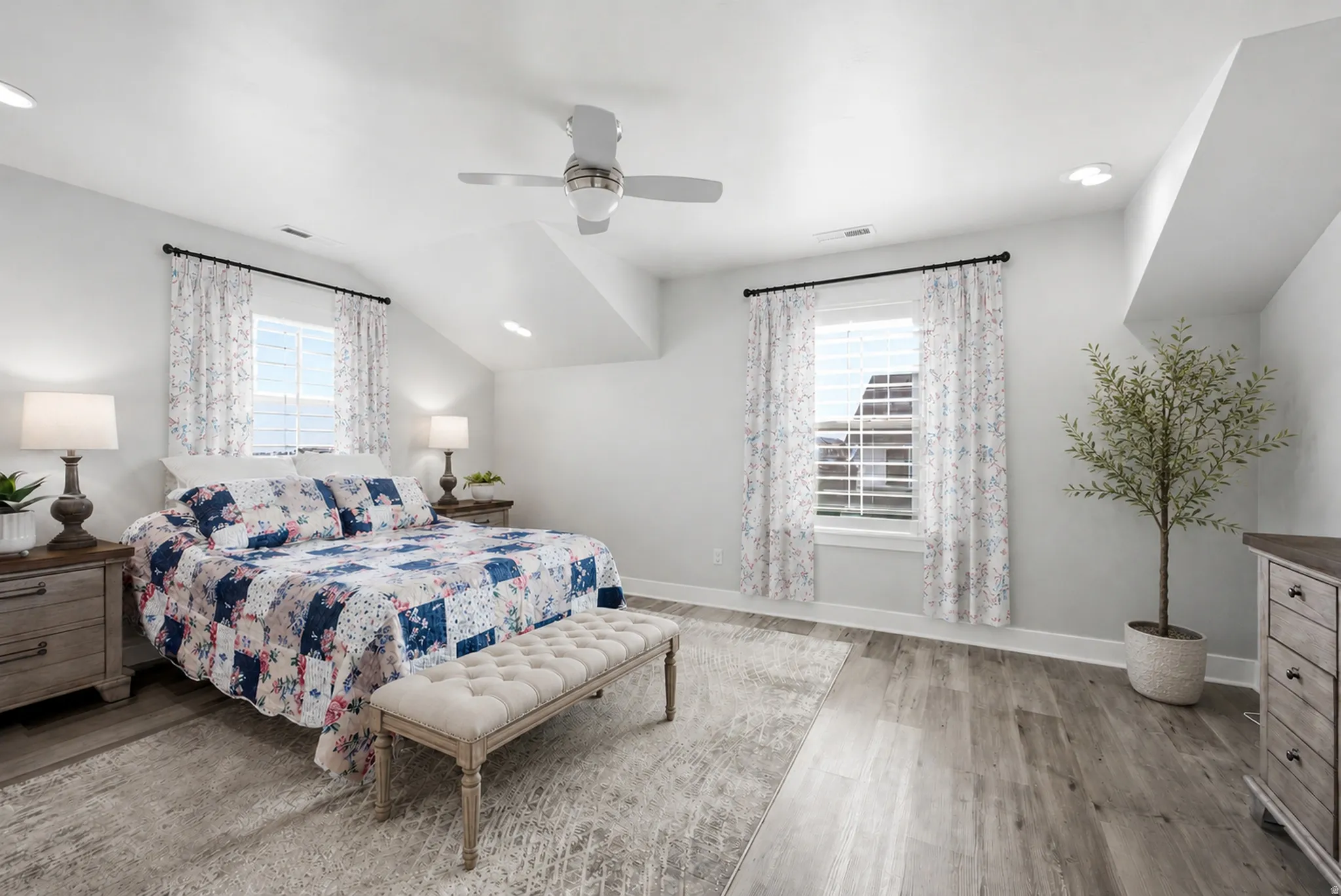 Spacious room featuring wood-finish flooring, two windows with blinds, a ceiling fan, recessed lighting, and sloped ceiling details