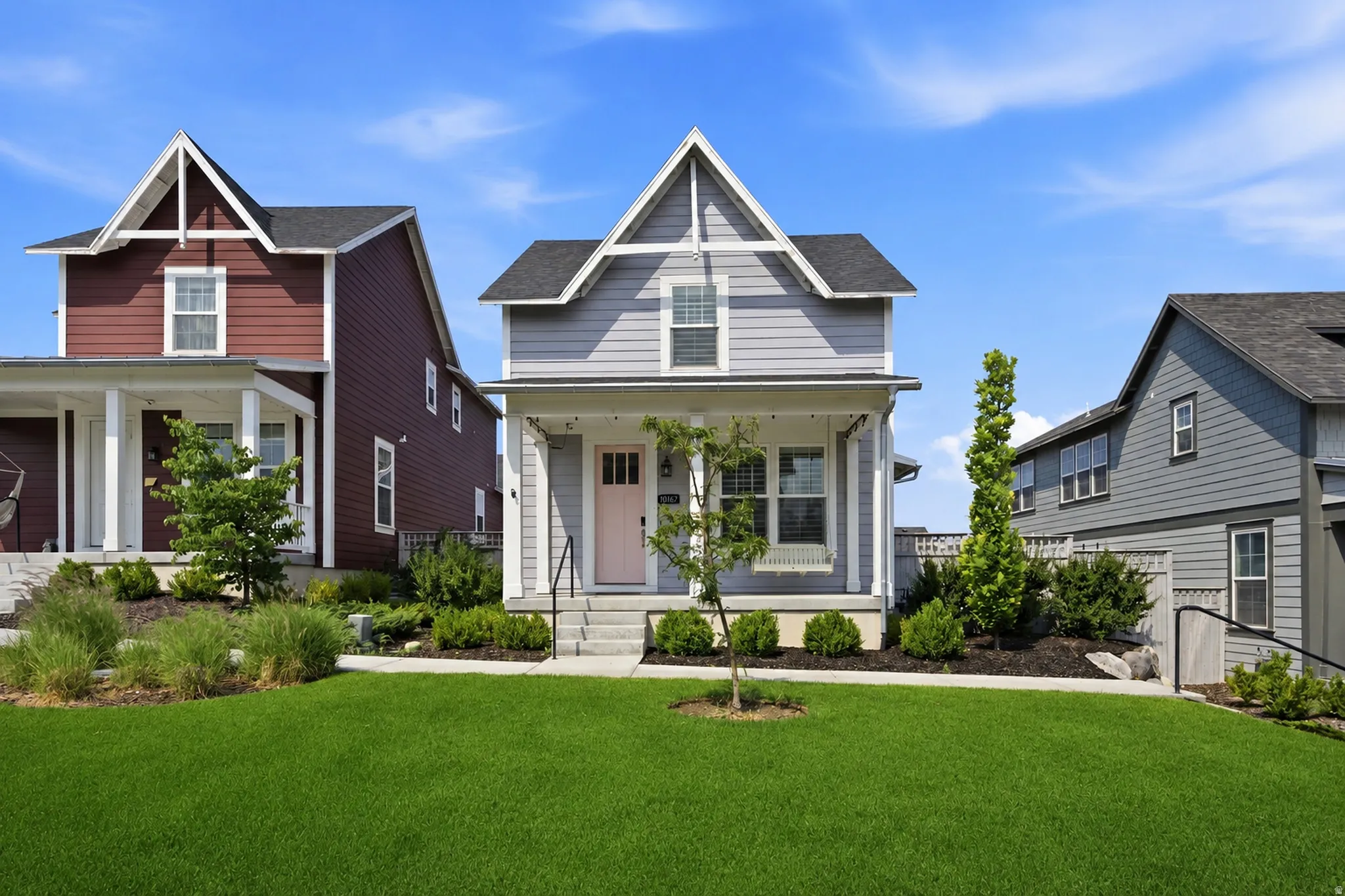 Light gray siding exterior featuring a covered porch with white columns, a pitched roof, and a pale pink entryway door
