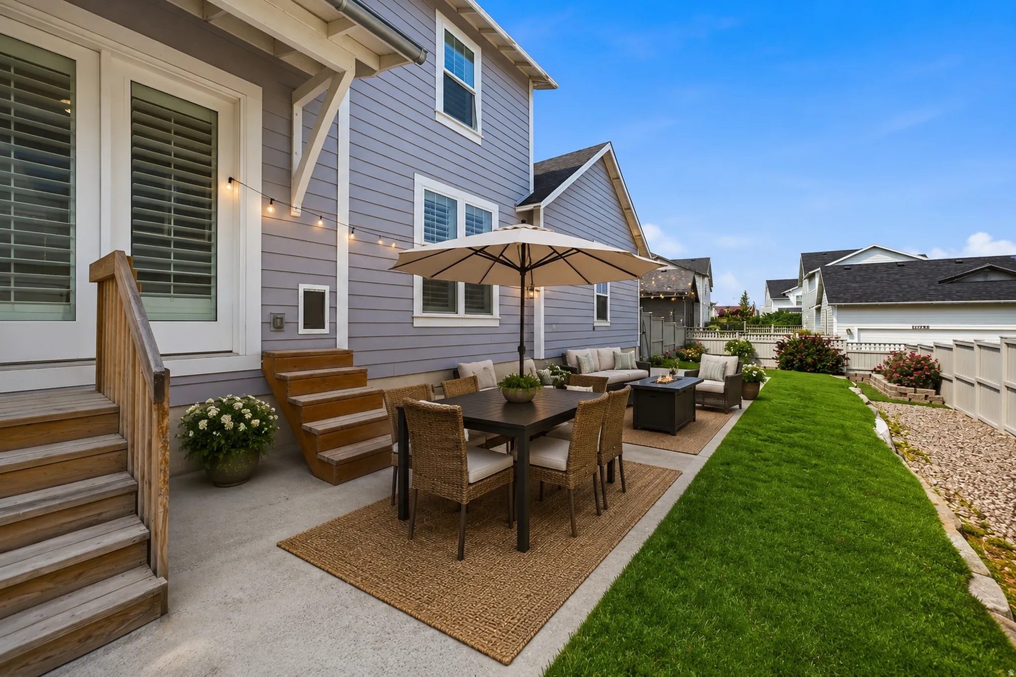 Expansive patio area featuring a concrete surface, a manicured lawn, a gravel border, and a privacy fence