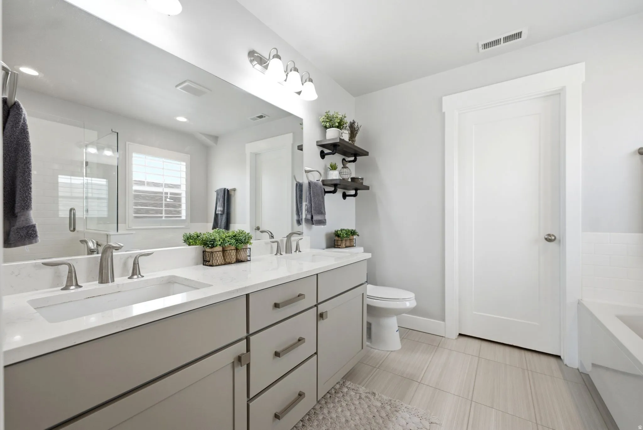 Double vanity with light gray cabinetry and white countertops