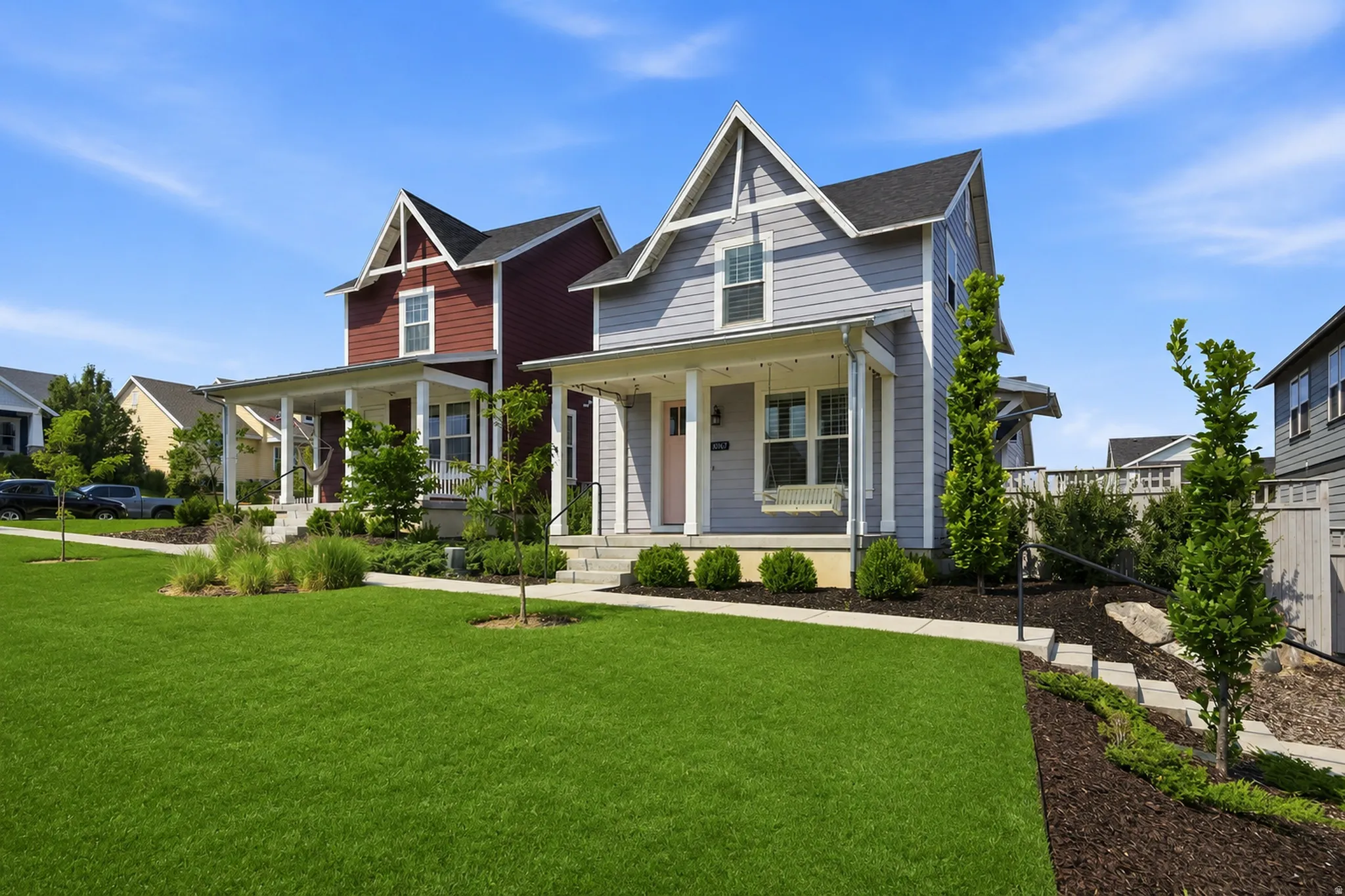 Charming light gray residence featuring a prominent front porch with a swing, white trim, and a gabled roofline