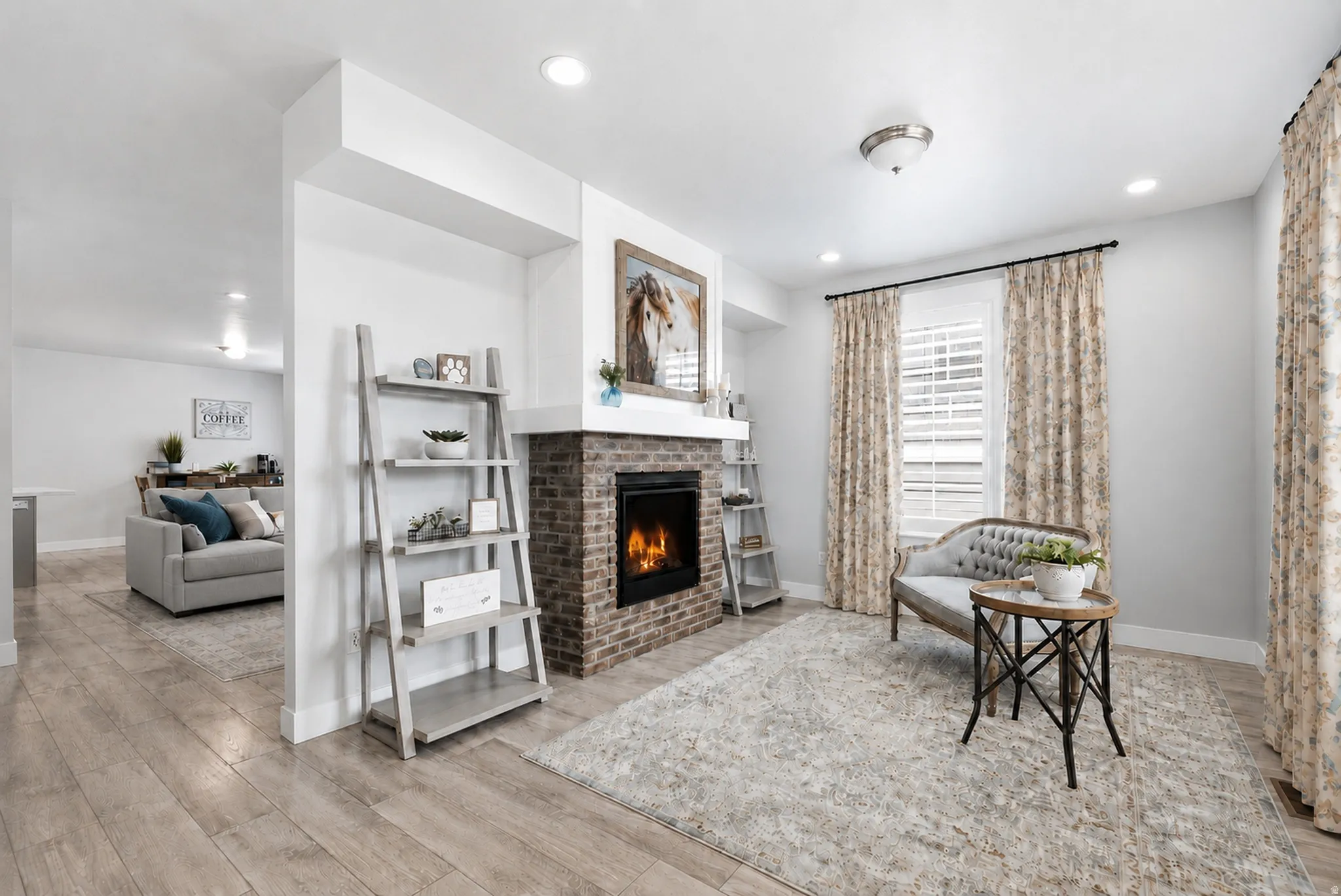 Living area featuring a brick-surround fireplace with a white mantel, recessed lighting, and wood-finish flooring