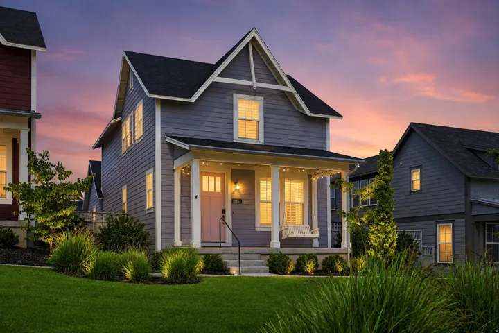 Charming two-story residence featuring a covered front porch with white columns, a pitched roofline, and light gray siding