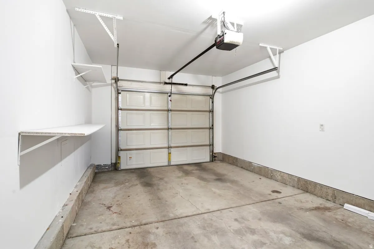 Single-car garage featuring a sectional garage door, concrete flooring, and built-in wall shelving
