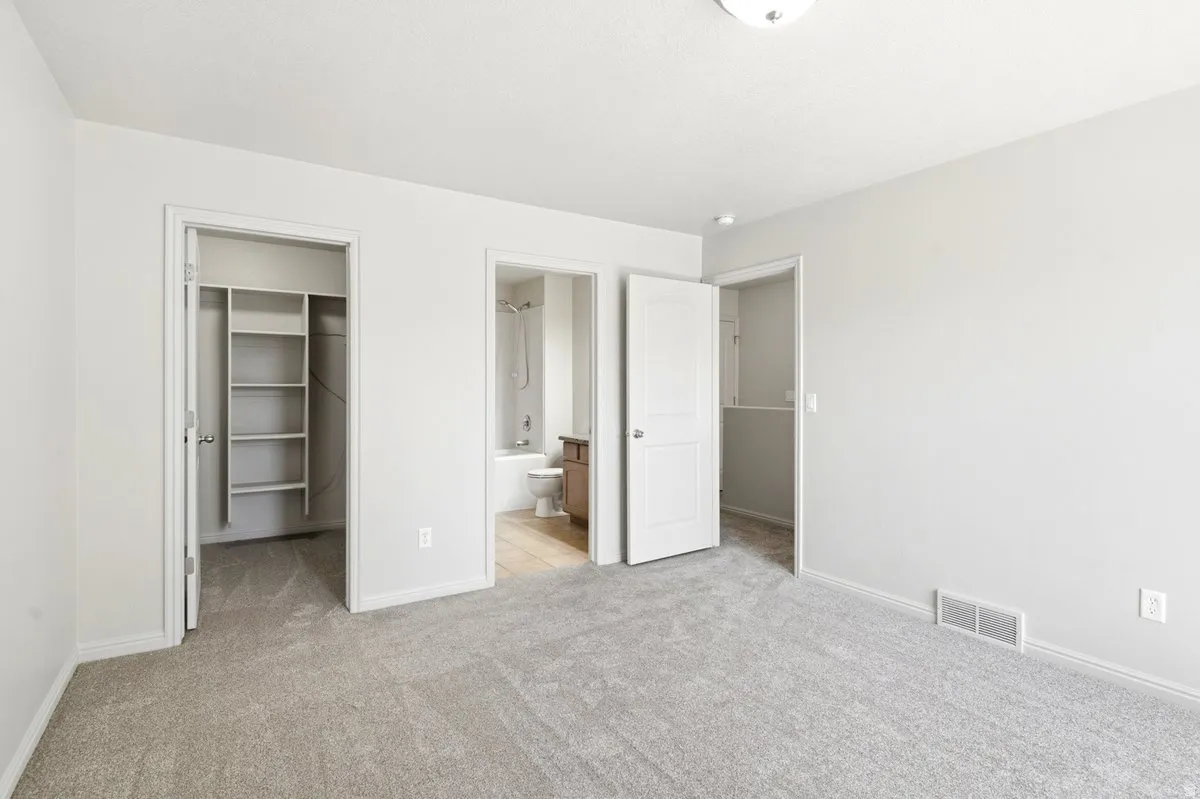 Spacious carpeted room featuring a ceiling light fixture, white trim, and light gray walls