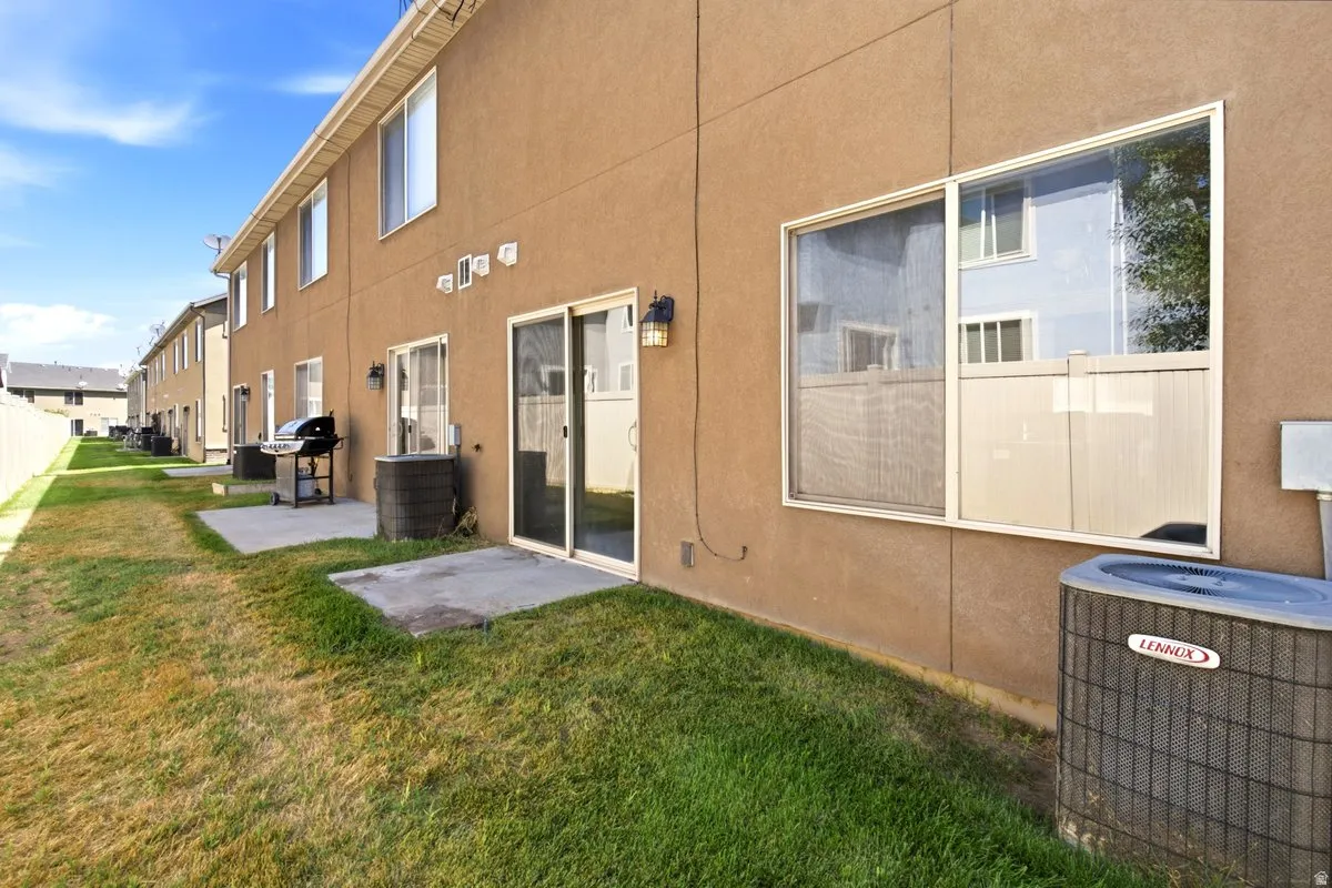 Private backyard patio featuring a sliding glass door, stucco exterior, and a white vinyl fence