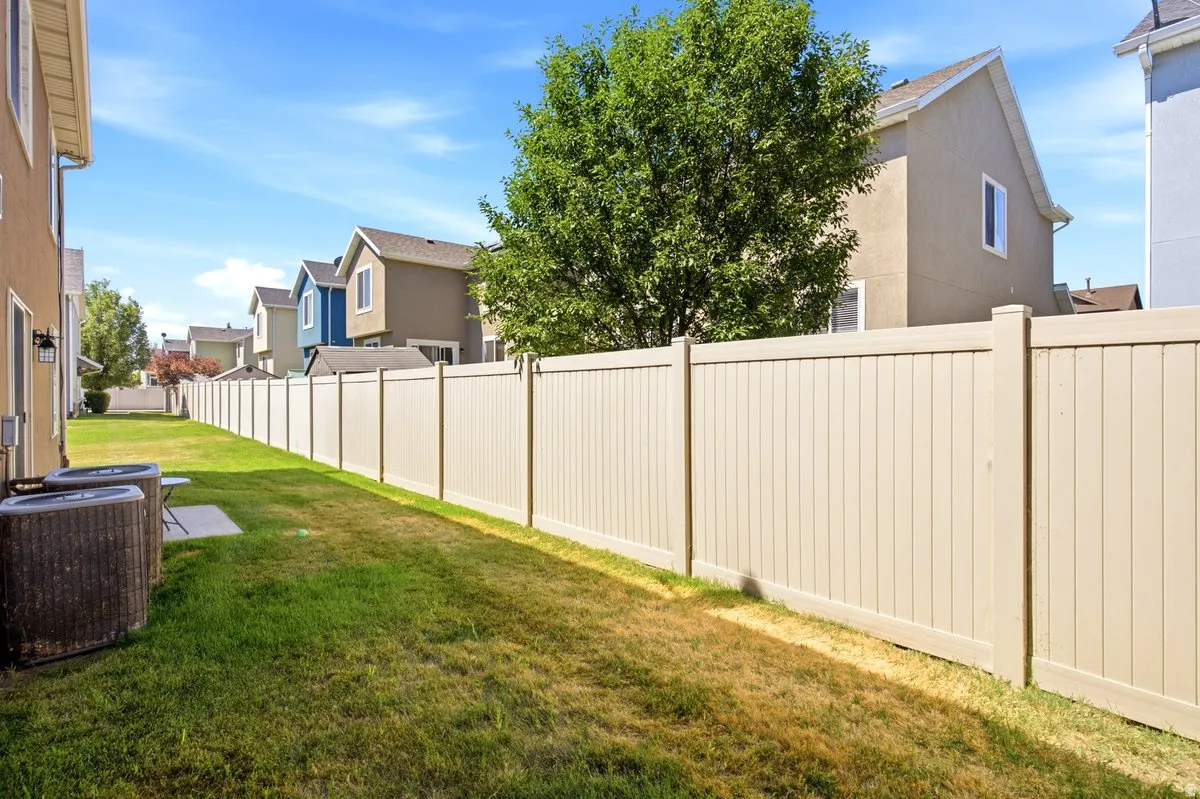 Expansive backyard featuring a full-height privacy fence, a verdant lawn, and a concrete pad