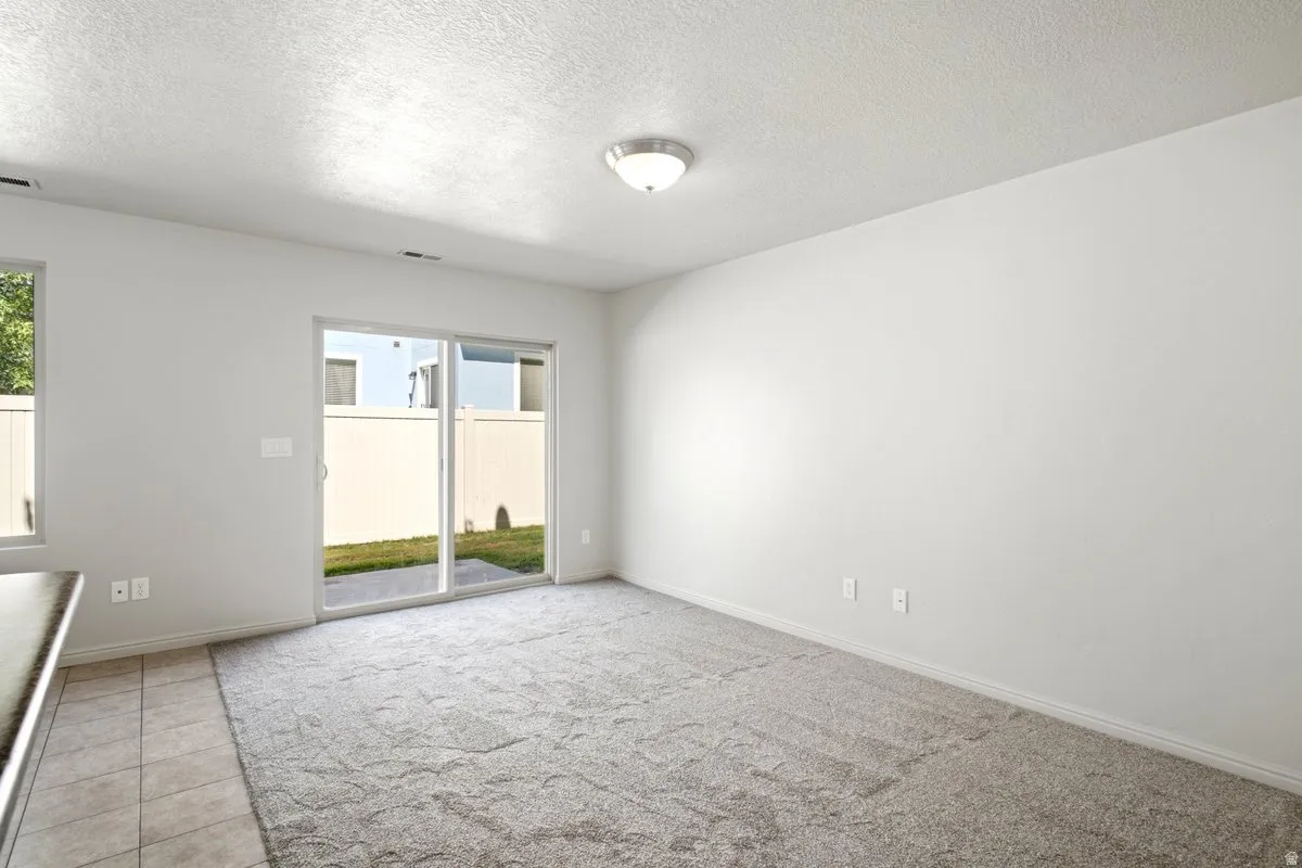 Spacious interior room featuring light-toned carpeting and neutral wall paint