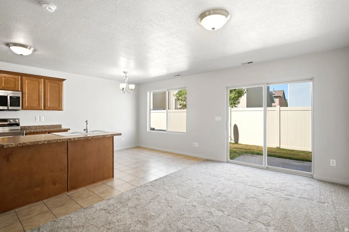 Open-concept living area featuring a kitchen island with integrated sink, stainless steel appliances, and wood-finish cabinetry