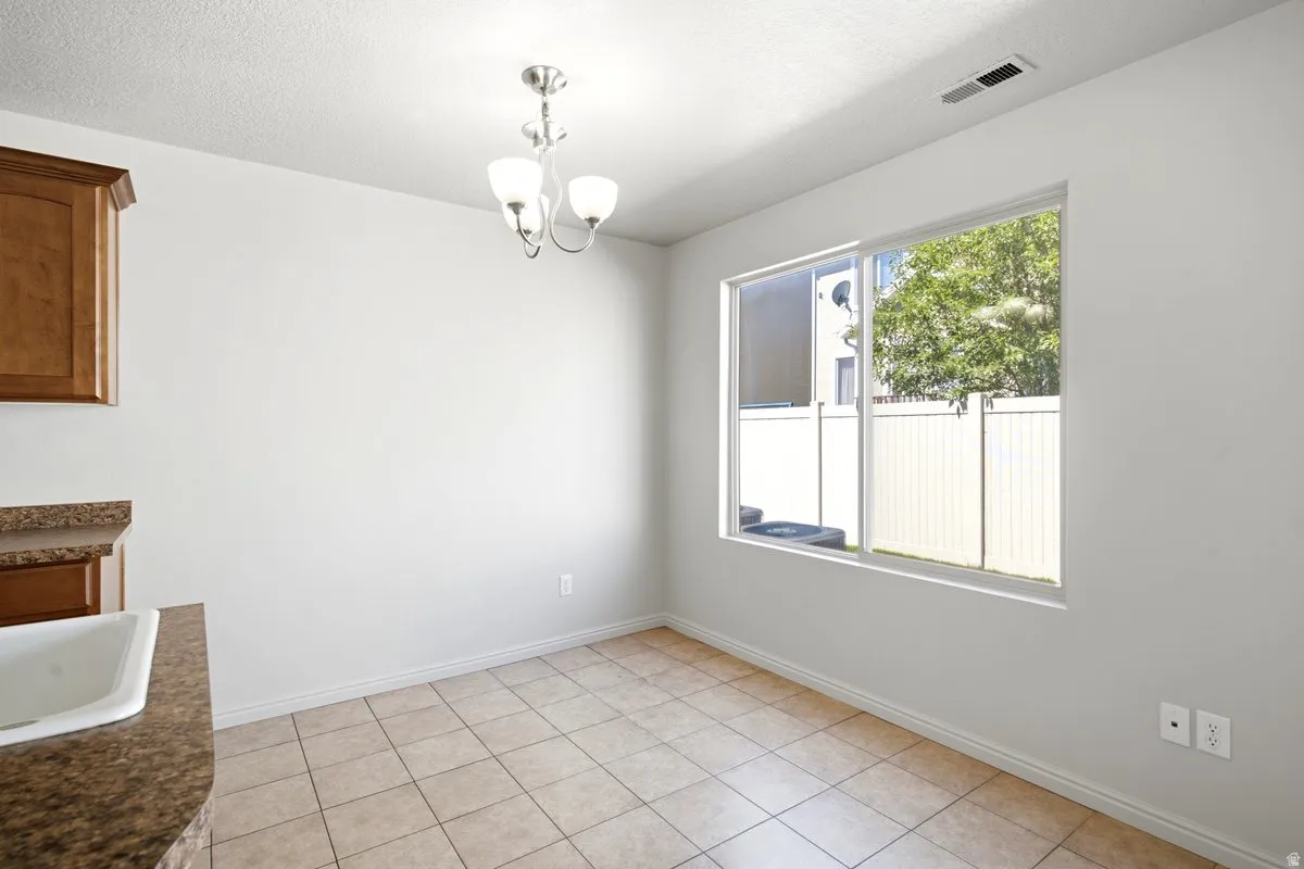 Ceramic tile flooring features, a silver-tone chandelier, and a large sliding window with white trim