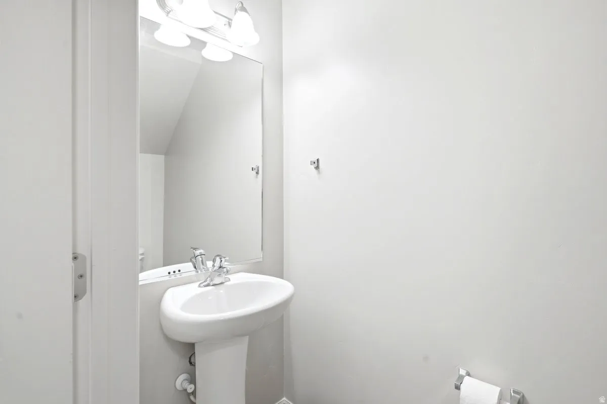 Pedestal sink with chrome faucet, large vanity mirror, and three-light fixture