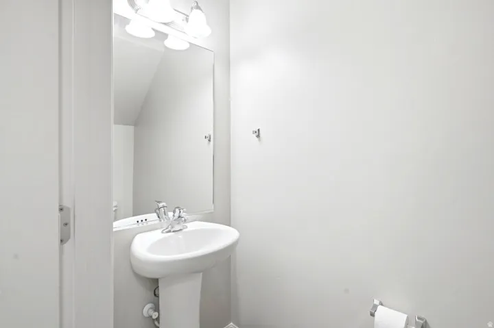 Pedestal sink with chrome faucet, large vanity mirror, and three-light fixture