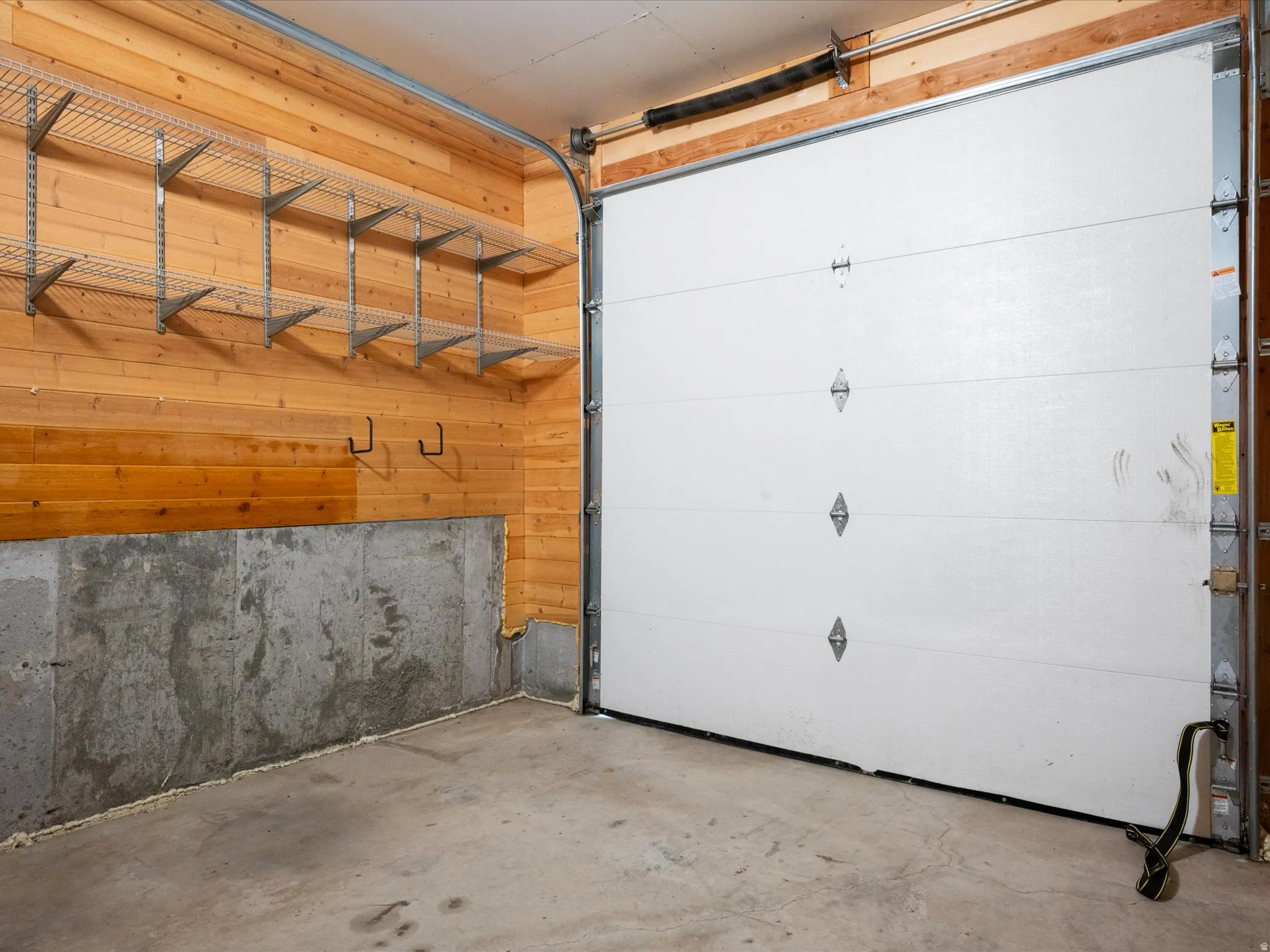Garage interior featuring wood-finish paneling, concrete foundation walls, and a concrete floor