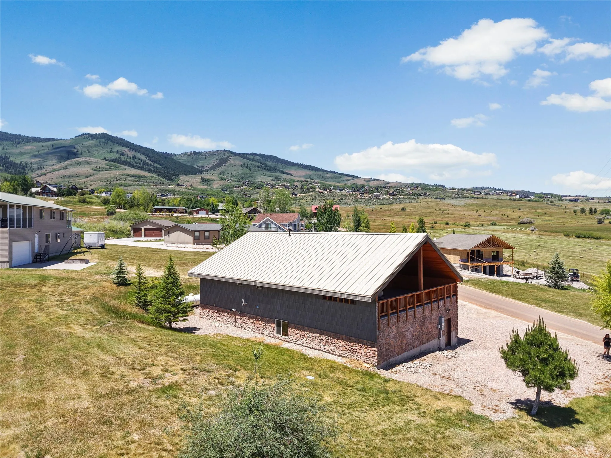 Contemporary structure featuring a metal roof, dark siding, and a stone-clad foundation