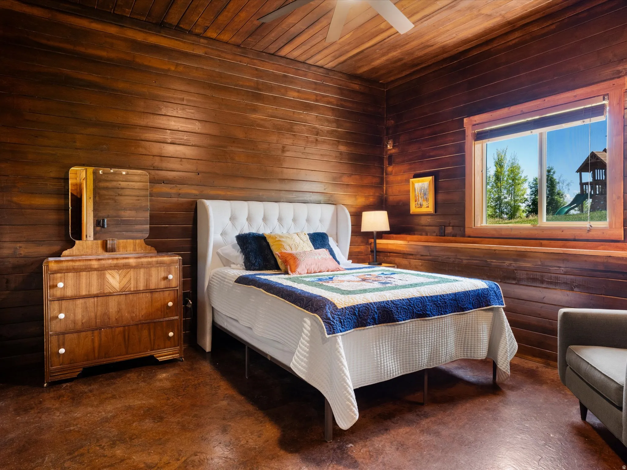 Interior space featuring wood-paneled walls and ceiling, a large window with wood trim, and textured flooring