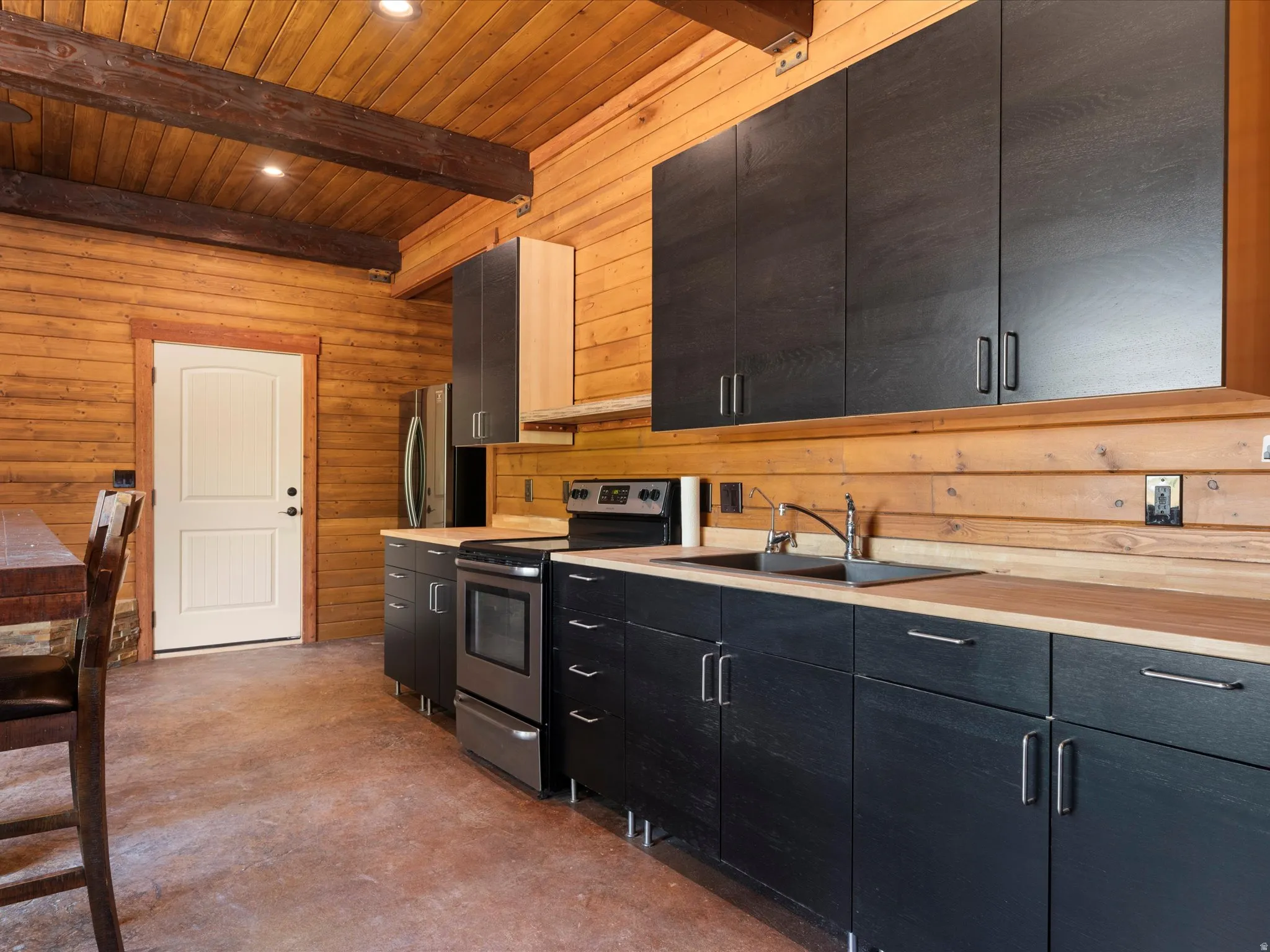 Kitchen featuring black cabinetry, wood-finish countertops, and stainless steel appliances