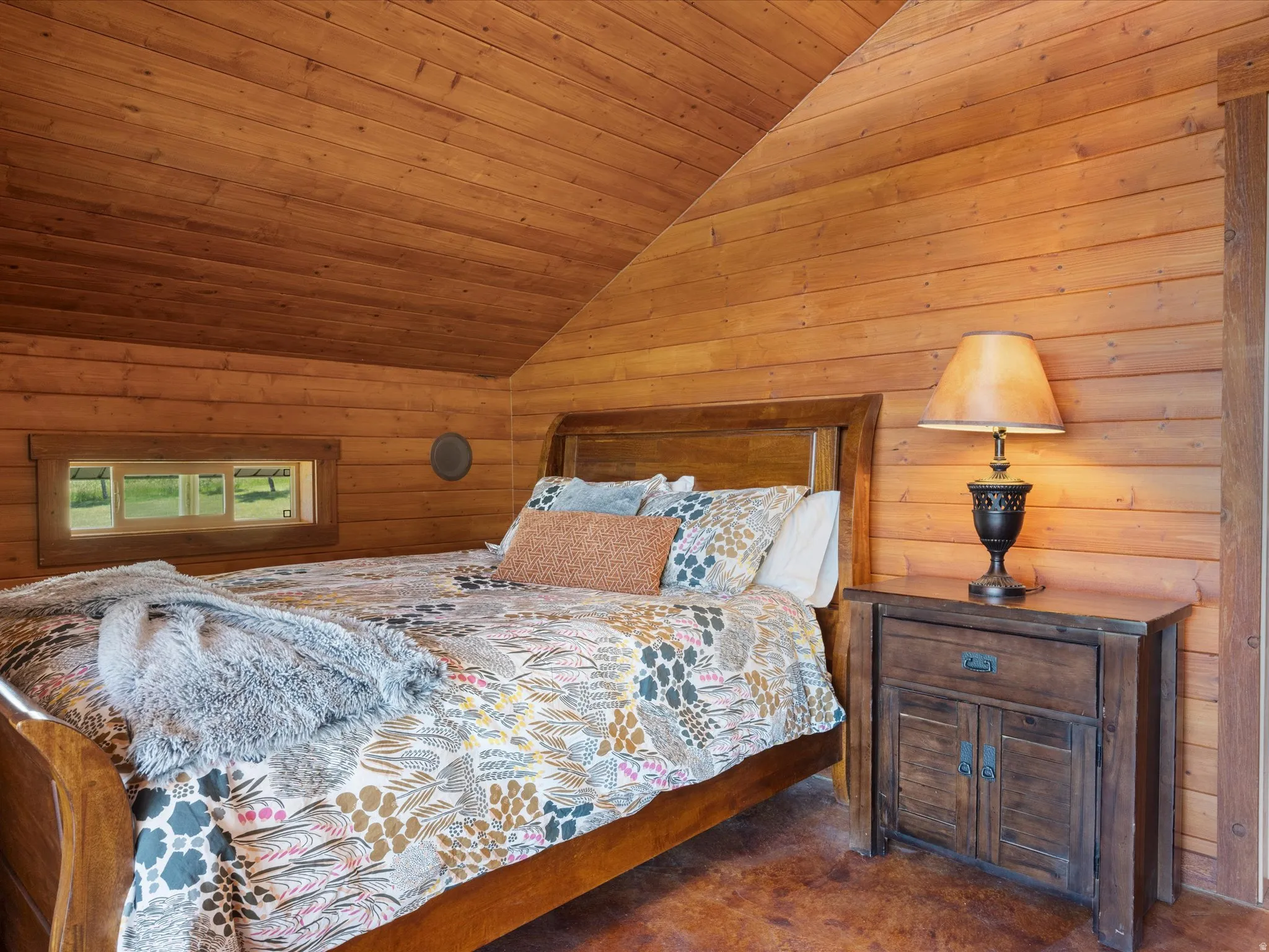 Wood-paneled room featuring an angled ceiling, horizontal wood wall paneling, a built-in horizontal window, and a built-in circular wall fixture