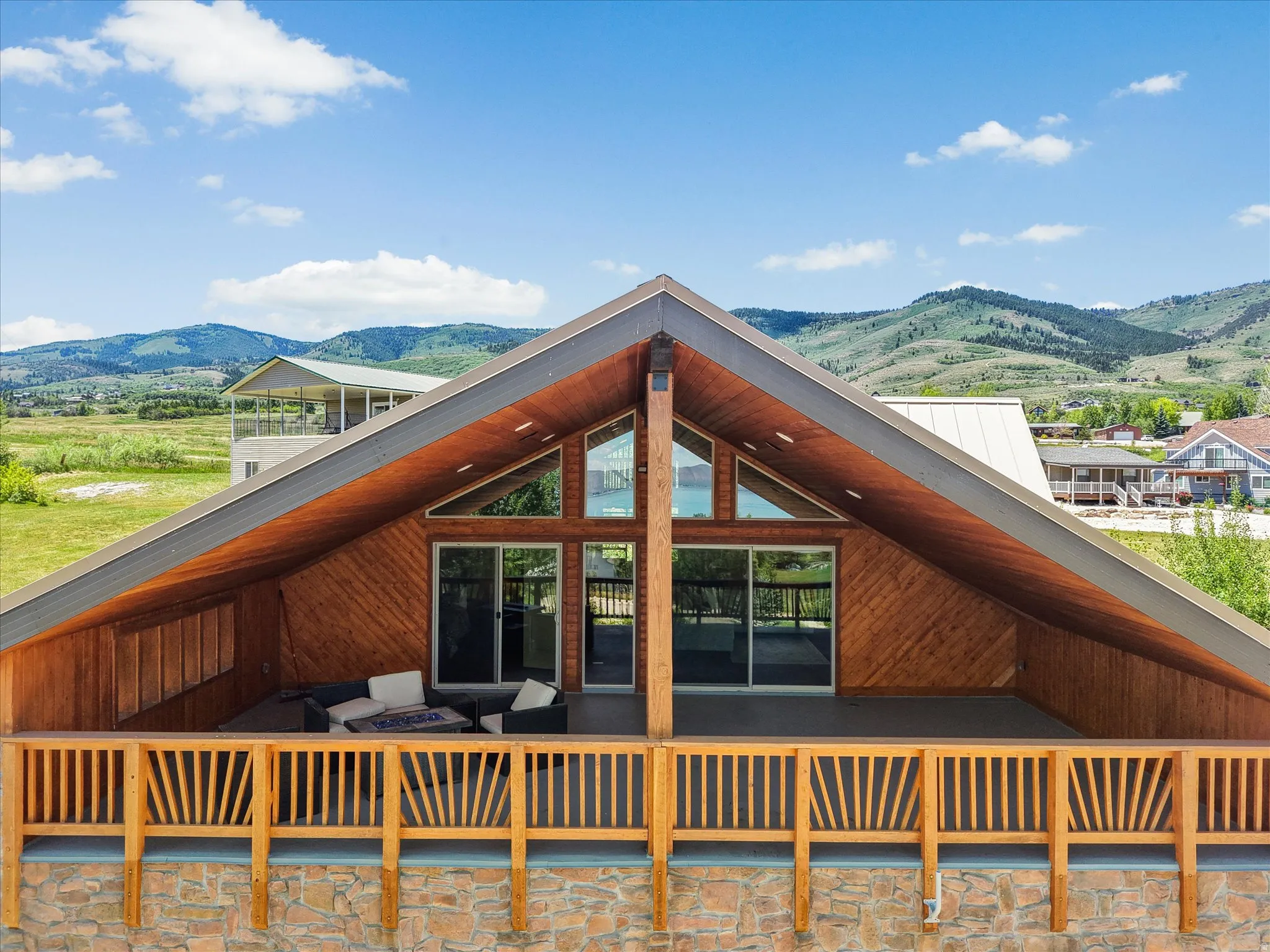 Expansive wood-paneled balcony featuring a sloped wood ceiling, large glass sliding doors, and triangular windows