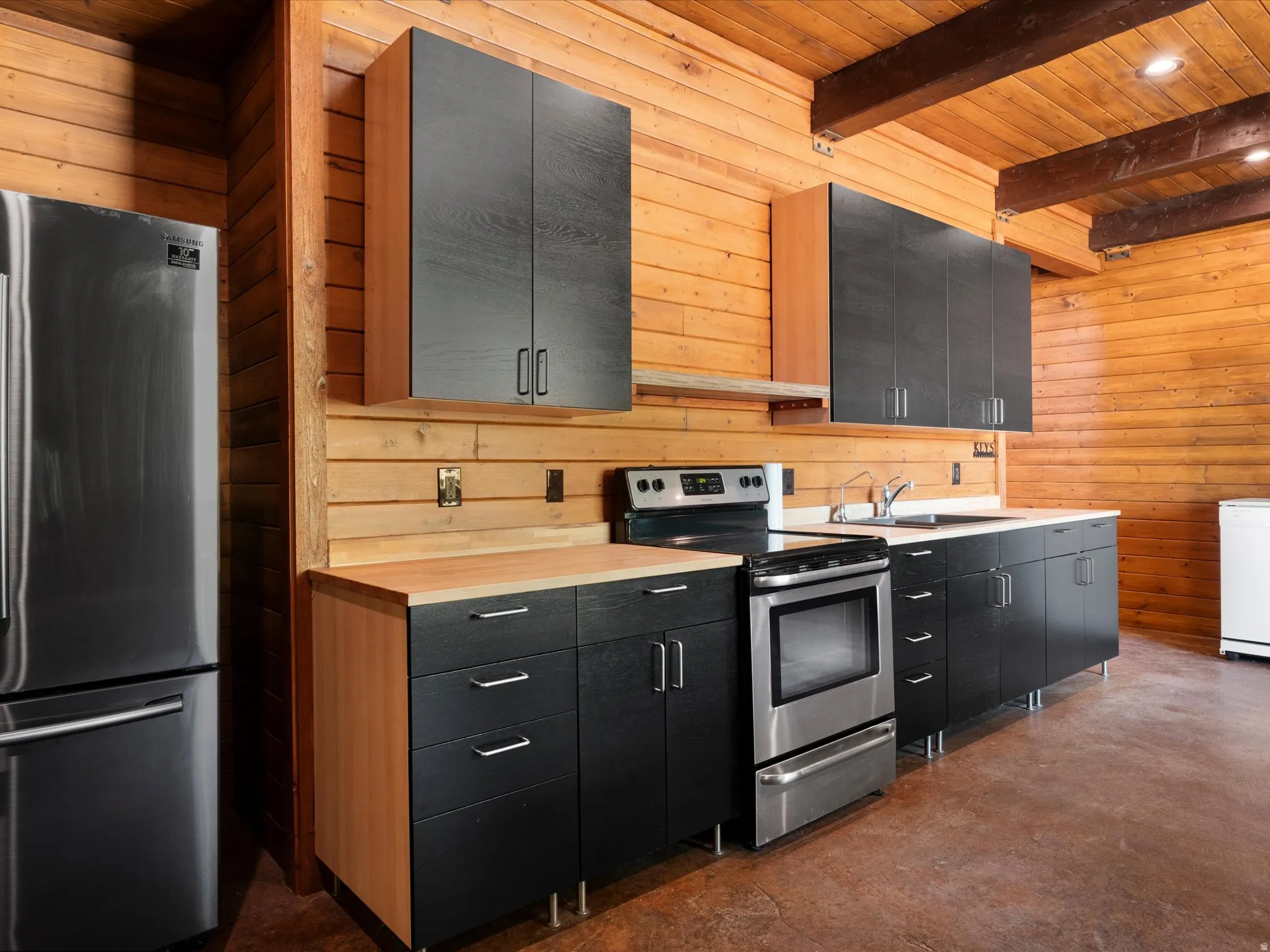 Kitchenette featuring wood-paneled walls and ceiling with exposed beams