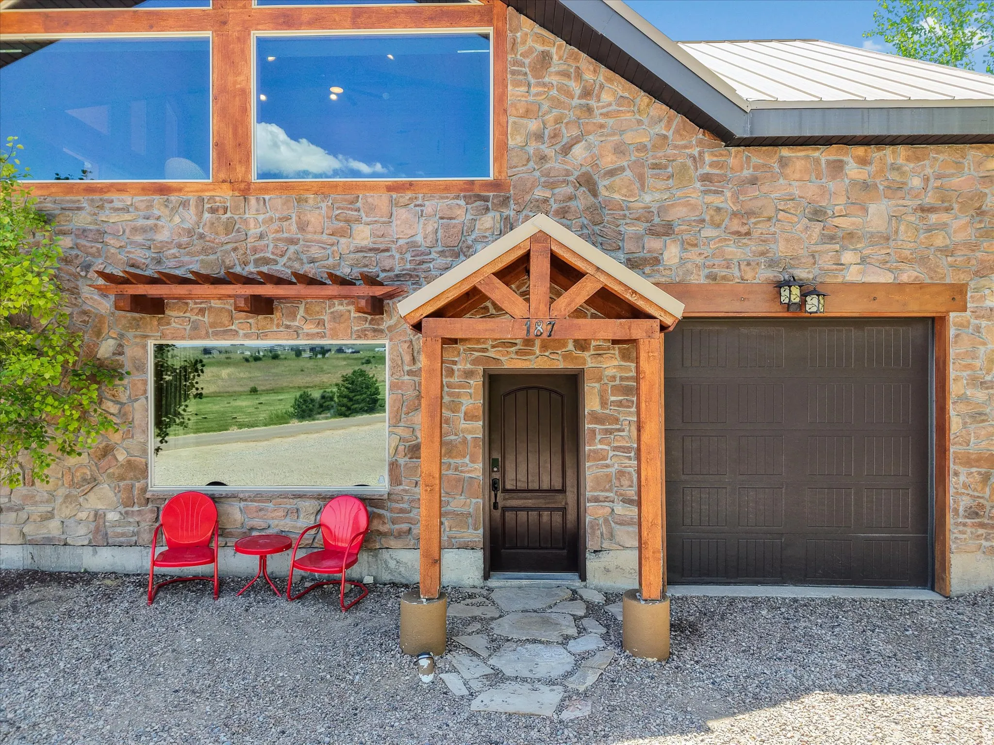Stone facade residence featuring a prominent wooden entry canopy, an arched paneled door, and a two-car garage with overhead lighting