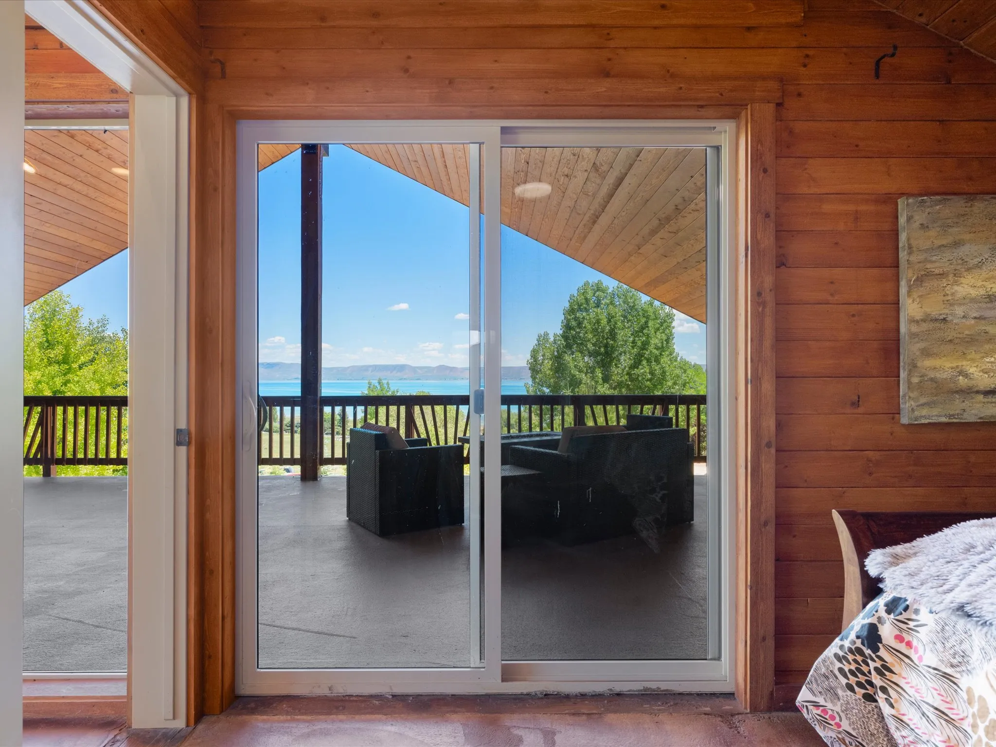 Sliding glass doors opening to an expansive deck with lake and mountain scenery