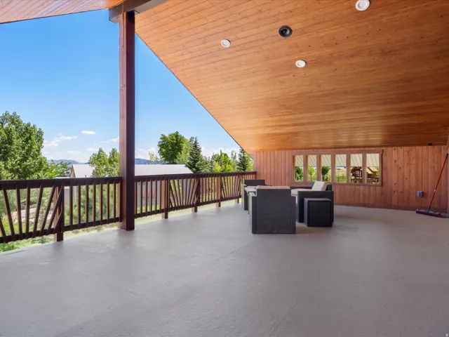 Spacious covered deck featuring a wood-panel ceiling, recessed lighting, and a wood railing with vertical balusters