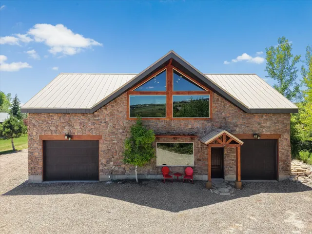 Stone facade home featuring a prominent peaked roofline and an upper-level window array