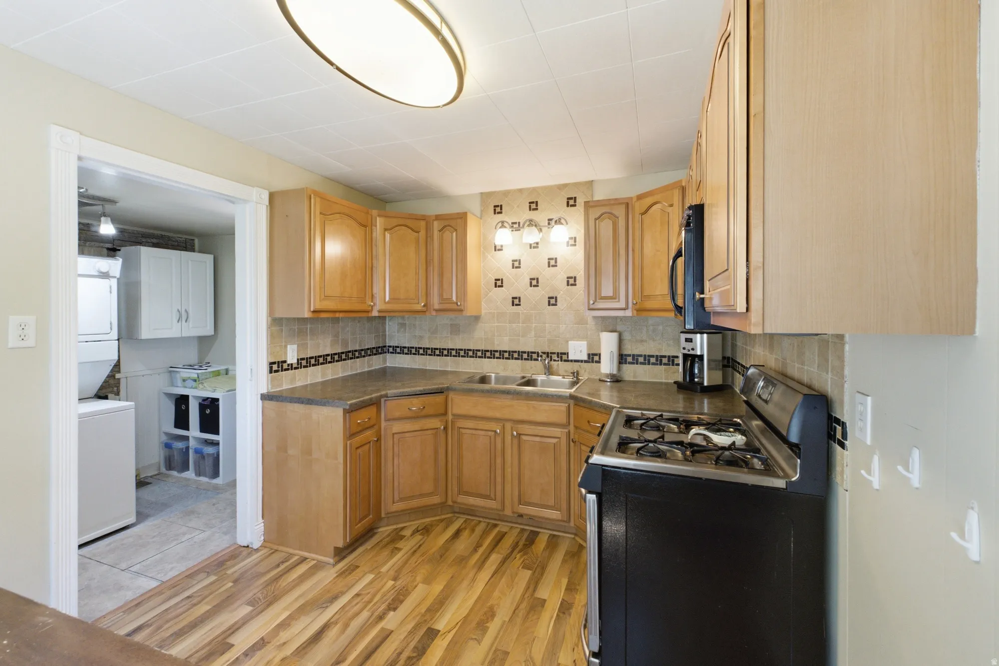 Functional kitchen with tile backsplash, generous cabinet storage, and adjoining laundry/utility room.