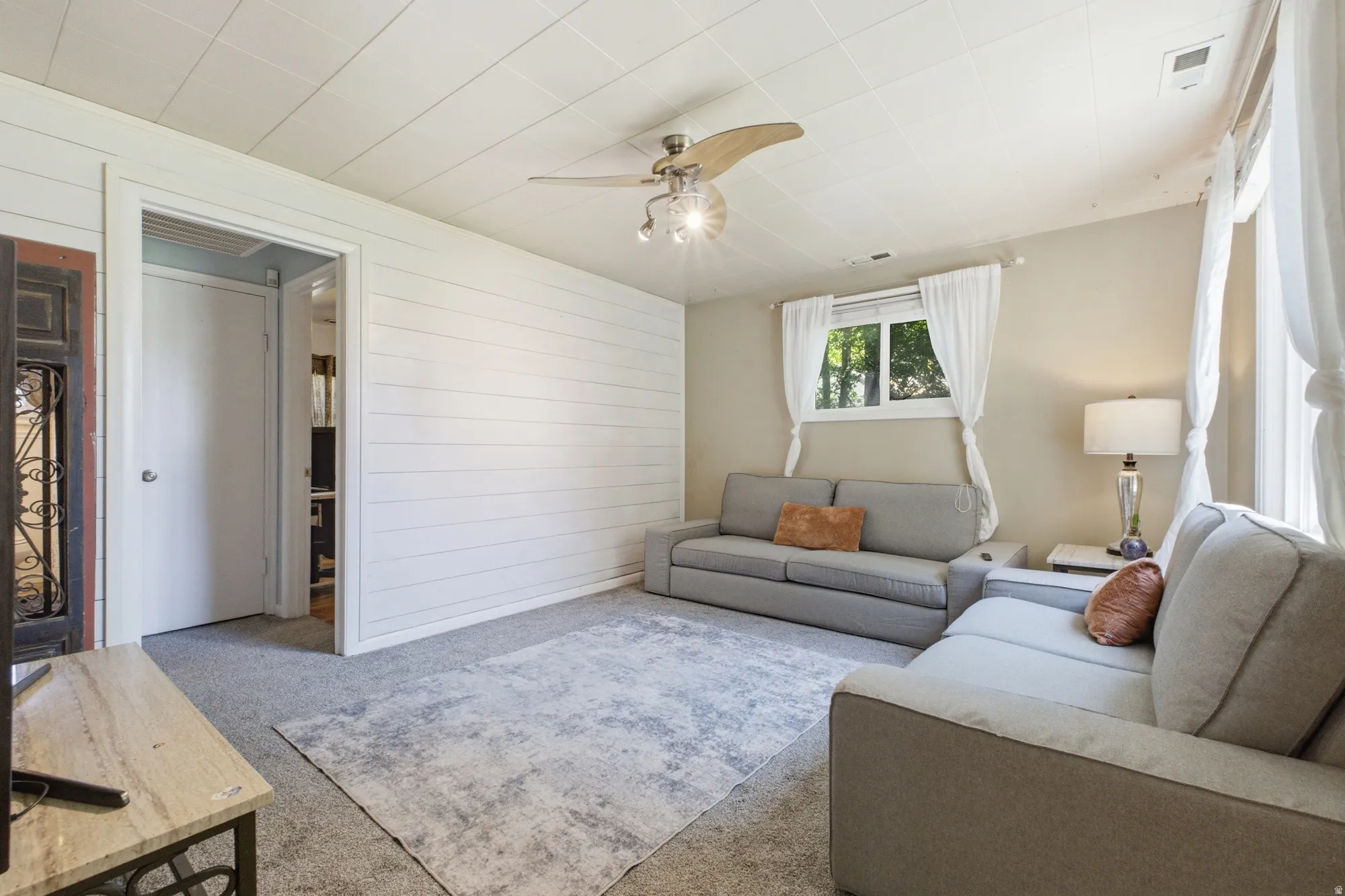 Spacious living area with shiplap accent wall detail, natural light, and easy flow to the adjoining rooms.