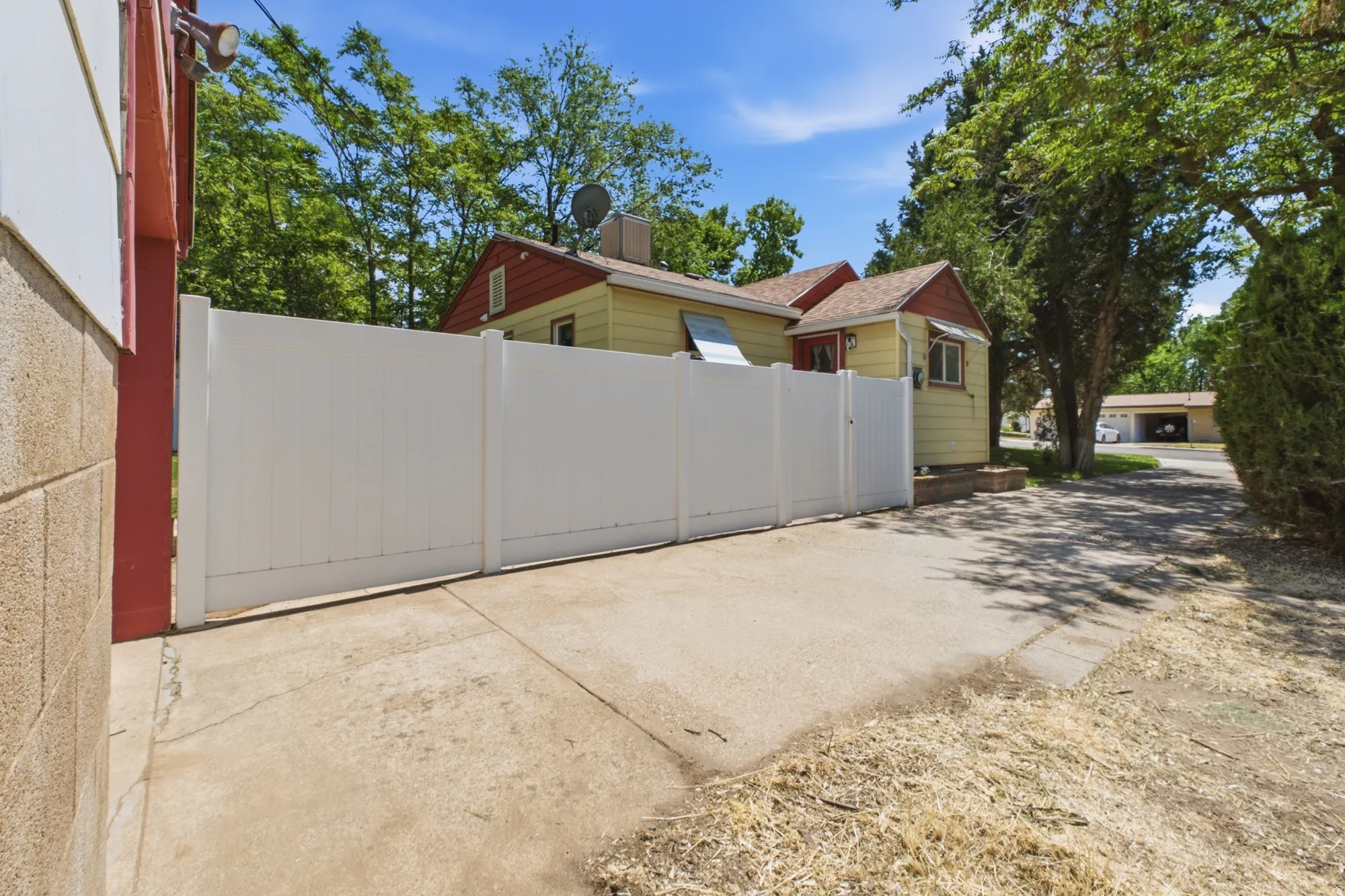 Side driveway area with vinyl fencing, gated access, and view of the home’s exterior.