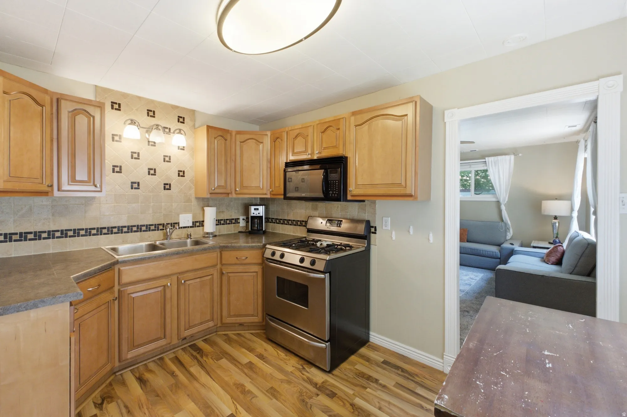 Kitchen view showing stainless appliances, warm cabinetry, and easy connection to the living room.