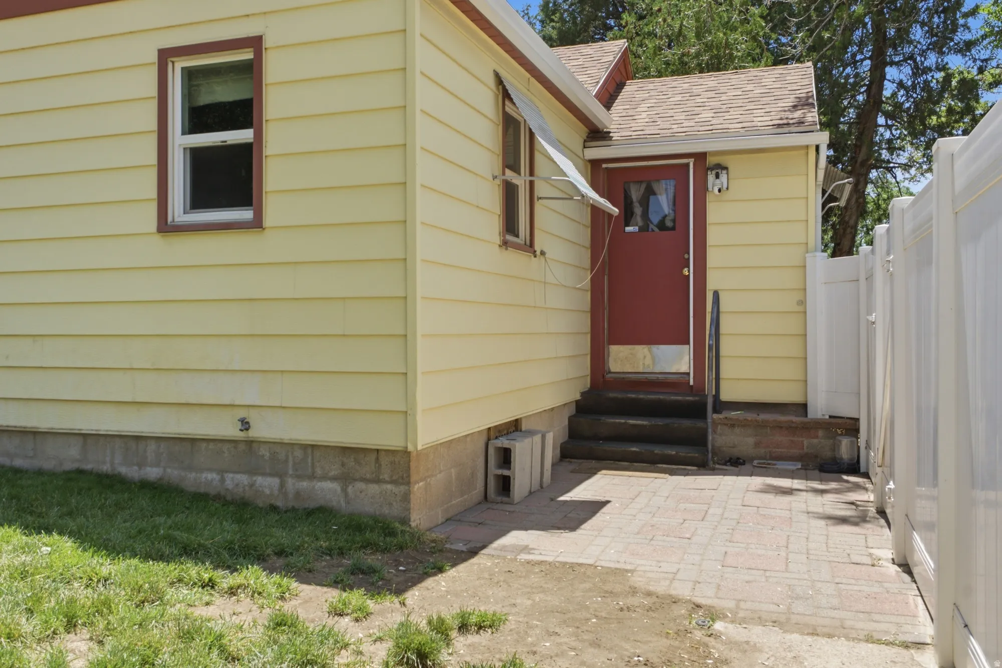 Rear entry with paved patio area, fenced access, and convenient connection to the backyard.